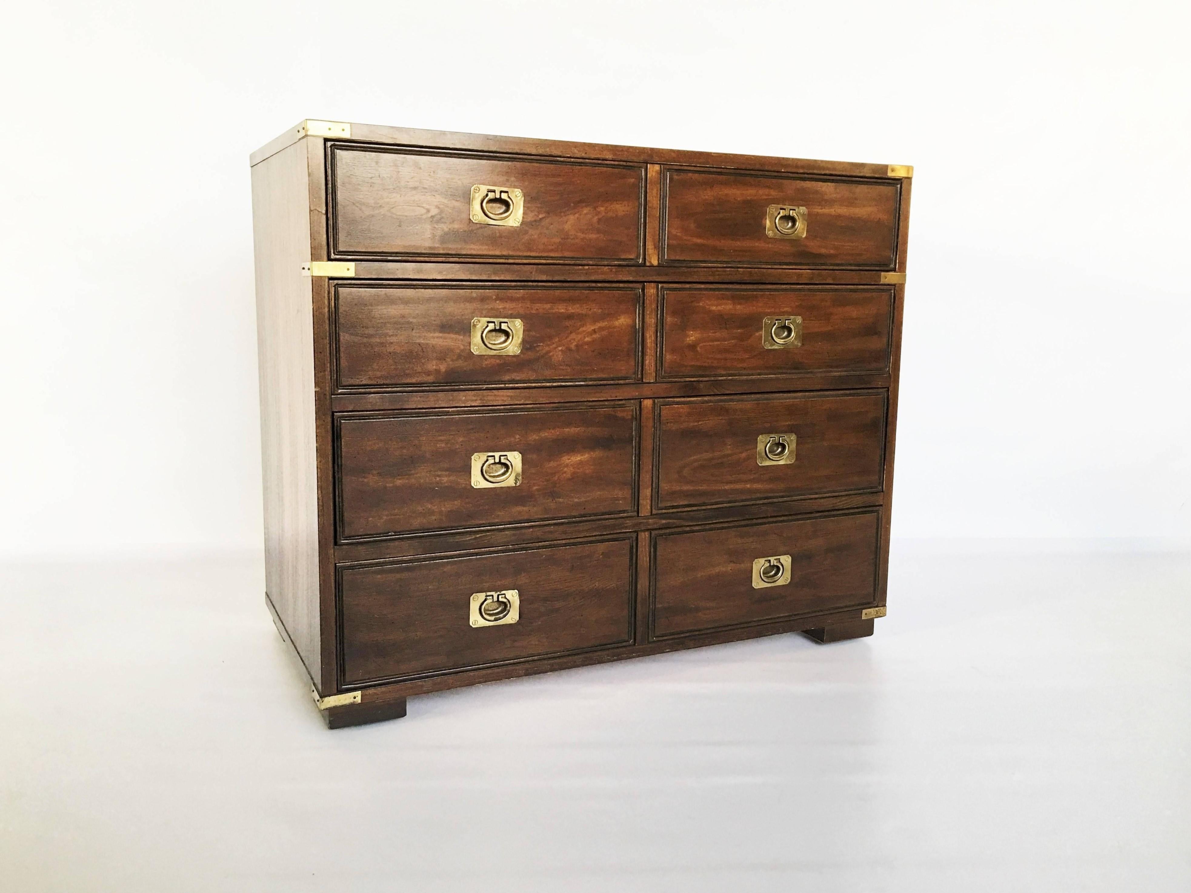 Military Officer's Campaign style bachelor chest by Thomasville. Featuring a handsome walnut exterior, showing eight equally divided short drawers. The brass-bound chest accented with brass hardware, resting on four rectangular feet. Can be