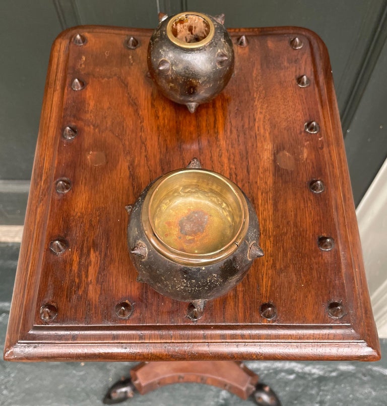 Military smoking table. Unusual Italian military style pedestal side table with polished wood grommeted scudo top holding “grenade” or mace style cigarette and match cups with match strike on slender baluster leg with central grenade on tri-form