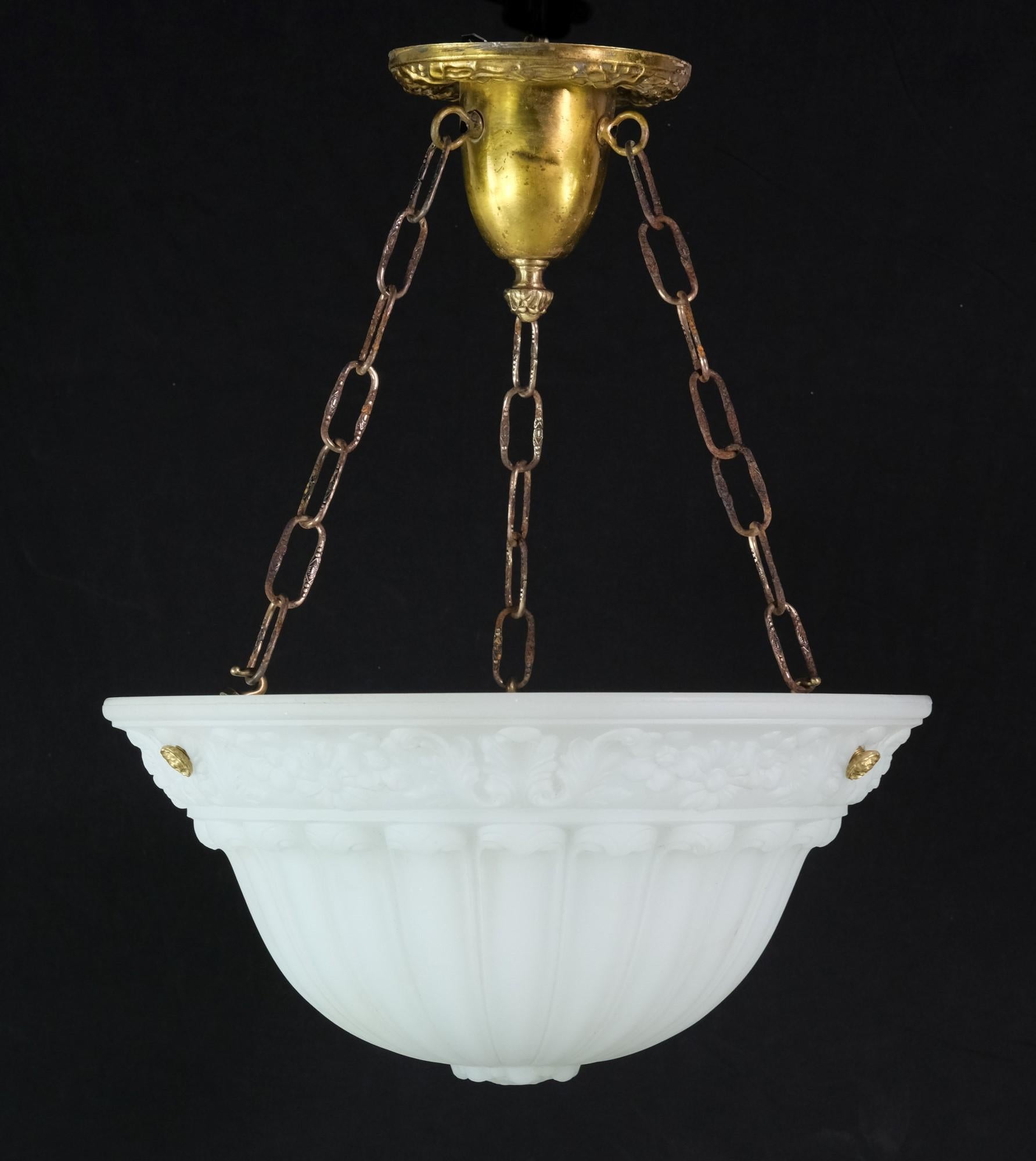 Antique pendant dish light with heavy milk glass bowl supported by brass canopy with brass plated steel chains. The white bowl has an elegant cast floral design which is complimented by a canopy with foliage details and three chains with brass
