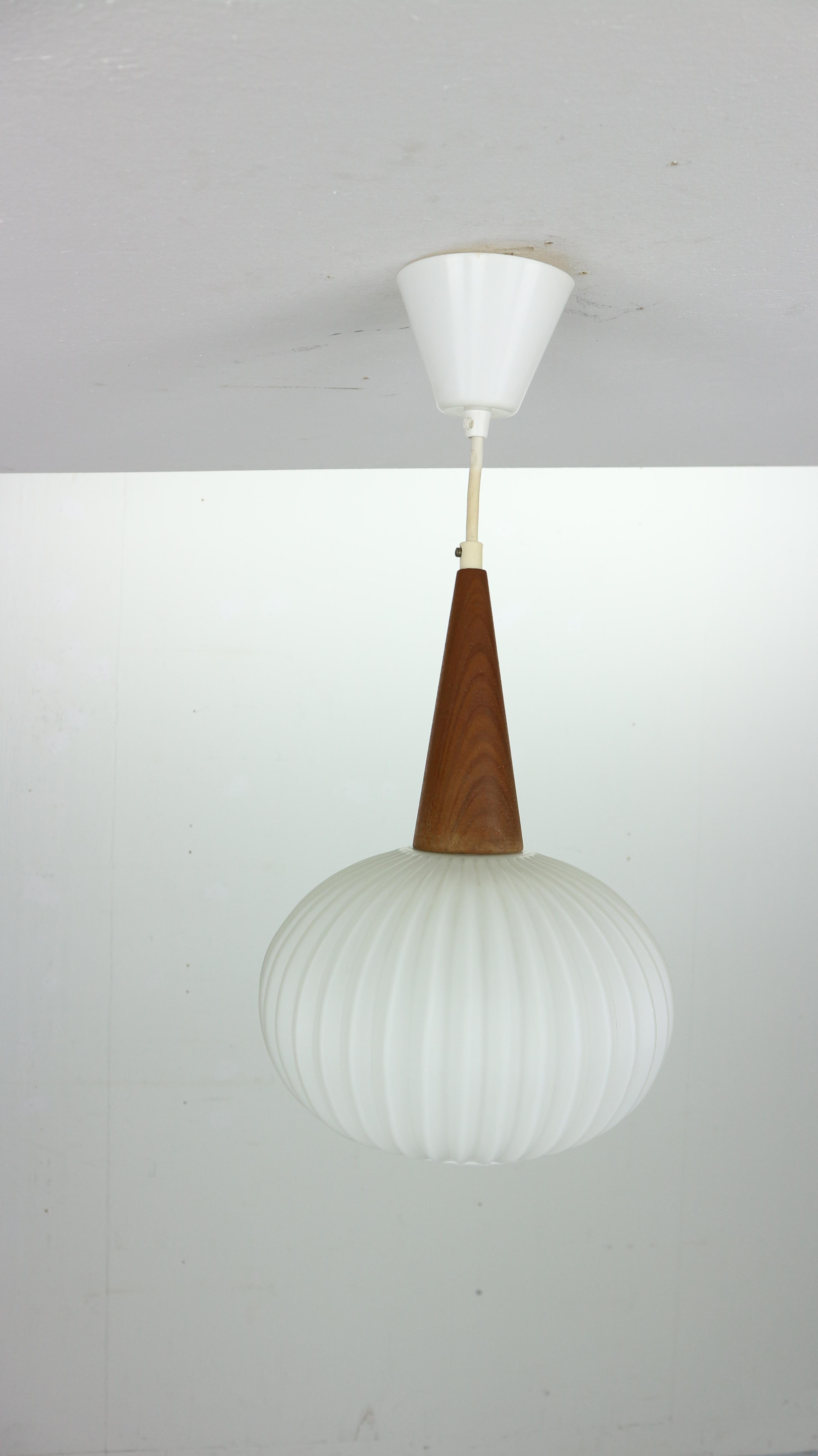 Vintage Mid-Century Modern design opal milk glass and teak pendant lamp designed by Louis Kalff and manufactured by Phillips in 1960s the Netherlands.
Elegant lamp provides warm and soft lightening.
 