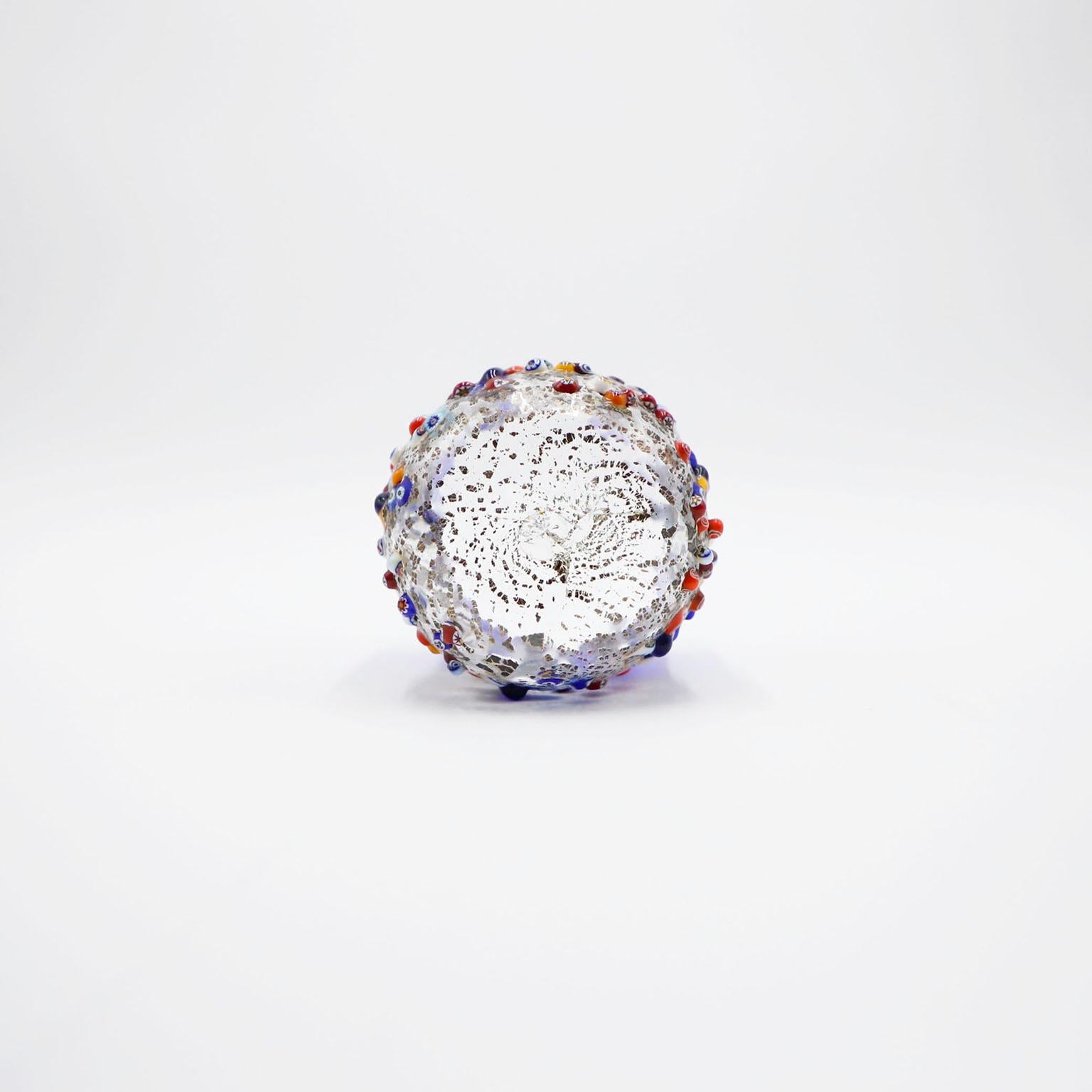 Precioso vaso de cristal millefiori de Murano con hoyuelos. Fabricada con cristal murrino y repujada con pan de plata y multicolor. Vidrio hecho a mano, único en su especie, cada pieza está firmada.

Añade esta hermosa pieza a tu colección de