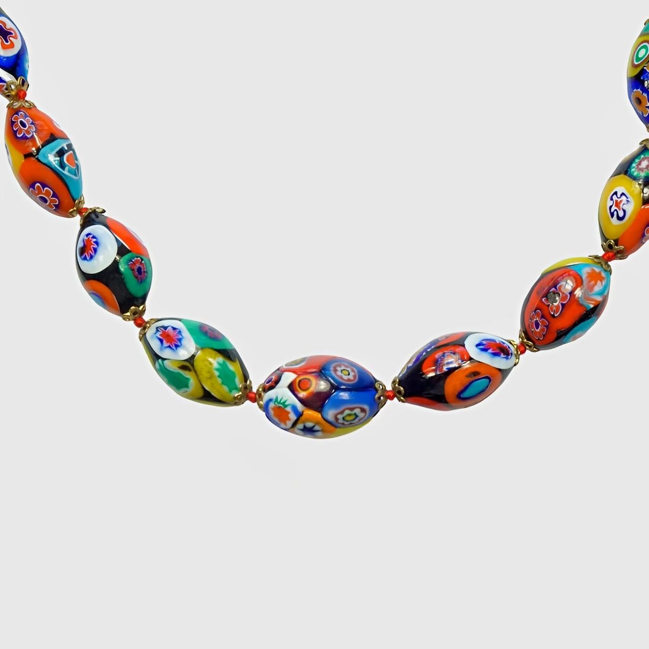 Millefiori Murano Glasperlenkette mit ovalen Perlen auf rotem, geknotetem Faden, mit goldfarbenen Kappen und einem Barrelverschluss. Die schönen bunten Perlen sind handgefertigt. Die Halskette ist in sehr gutem Zustand.

Messlänge 74 cm / 29,1 Zoll,