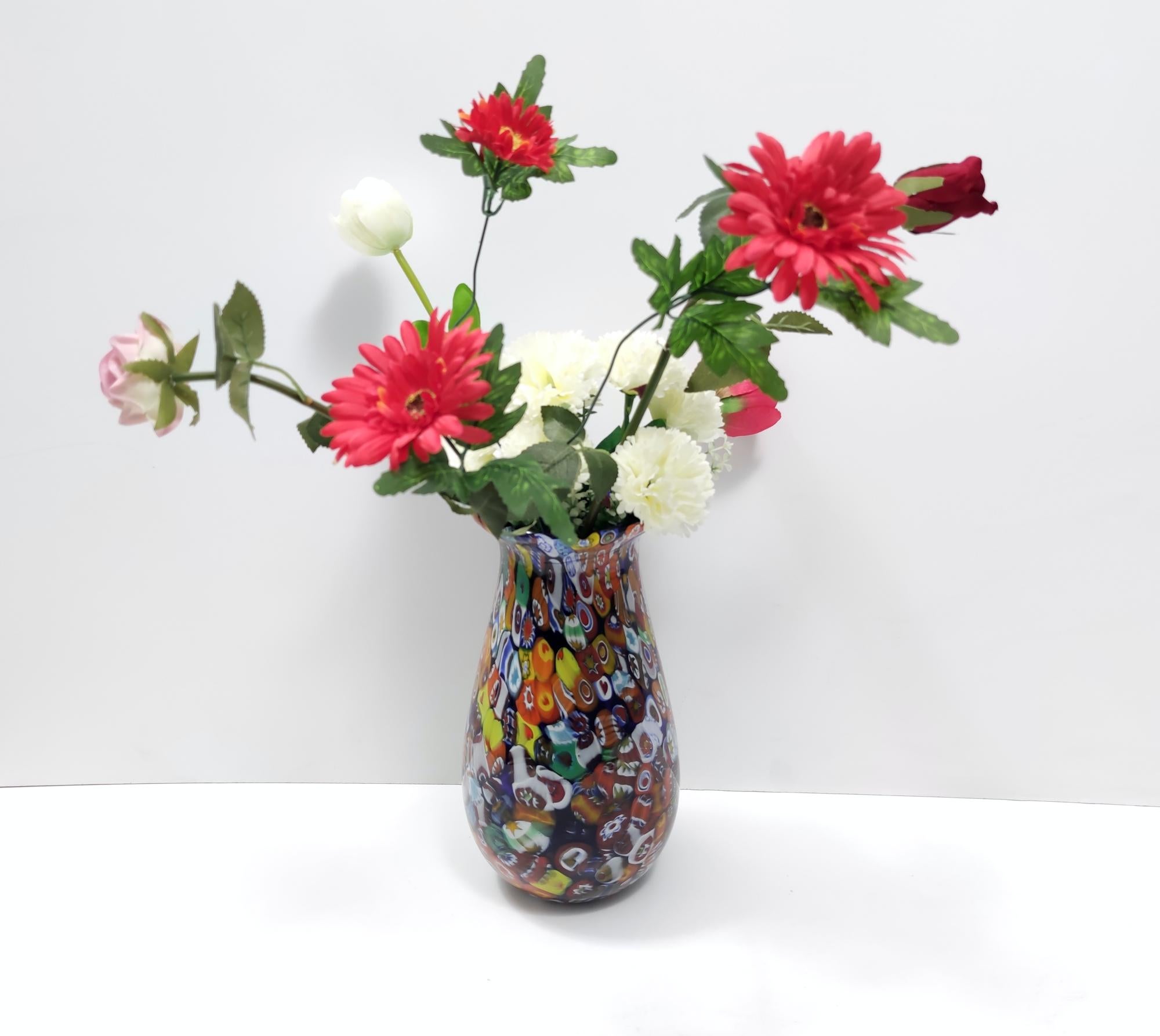 This is a Murano glass multi-colored millefiori vase. 
It has a multitude of different murrines, in a rainbow of colors.
It is a vintage item, therefore it might show slight traces of use, but it can be considered as in perfect original condition