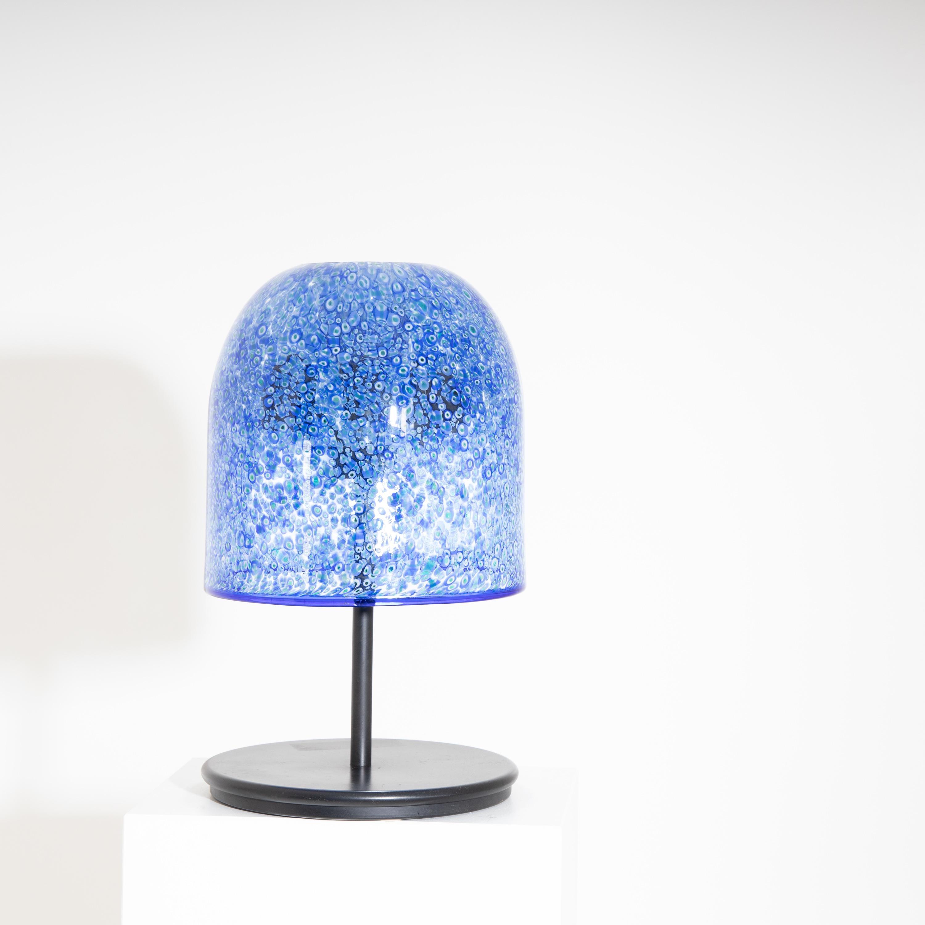 Table lamp standing on a round black metal base with a large bell-shaped glass shade in blue, made in Millefiori technique.
For the electrification we assume no liability and no warranty.