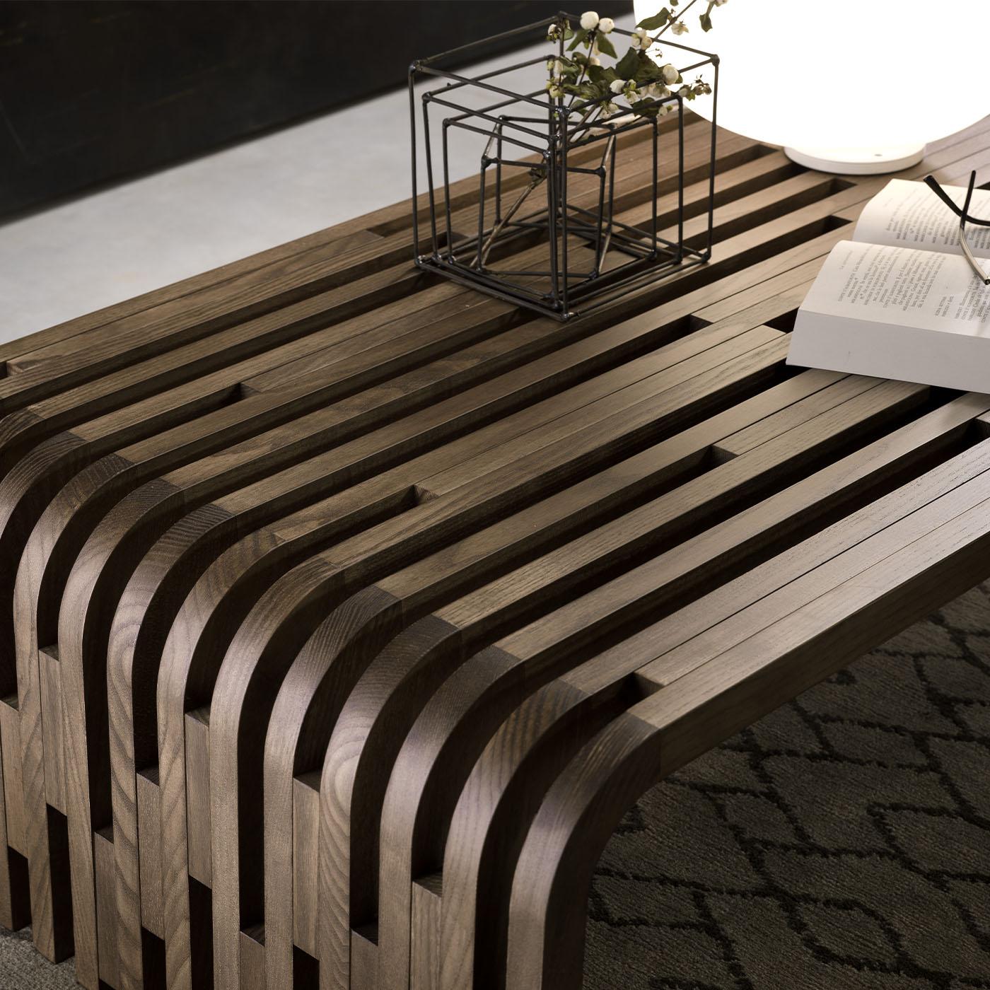 Cette table d'appoint originale pour canapé, conçue par Norberto Delfinetti et Monica Bernasconi, est fabriquée en bois de noyer massif, capturant la beauté naturelle de l'extérieur. Le plateau en verre crée un contraste saisissant mais harmonieux