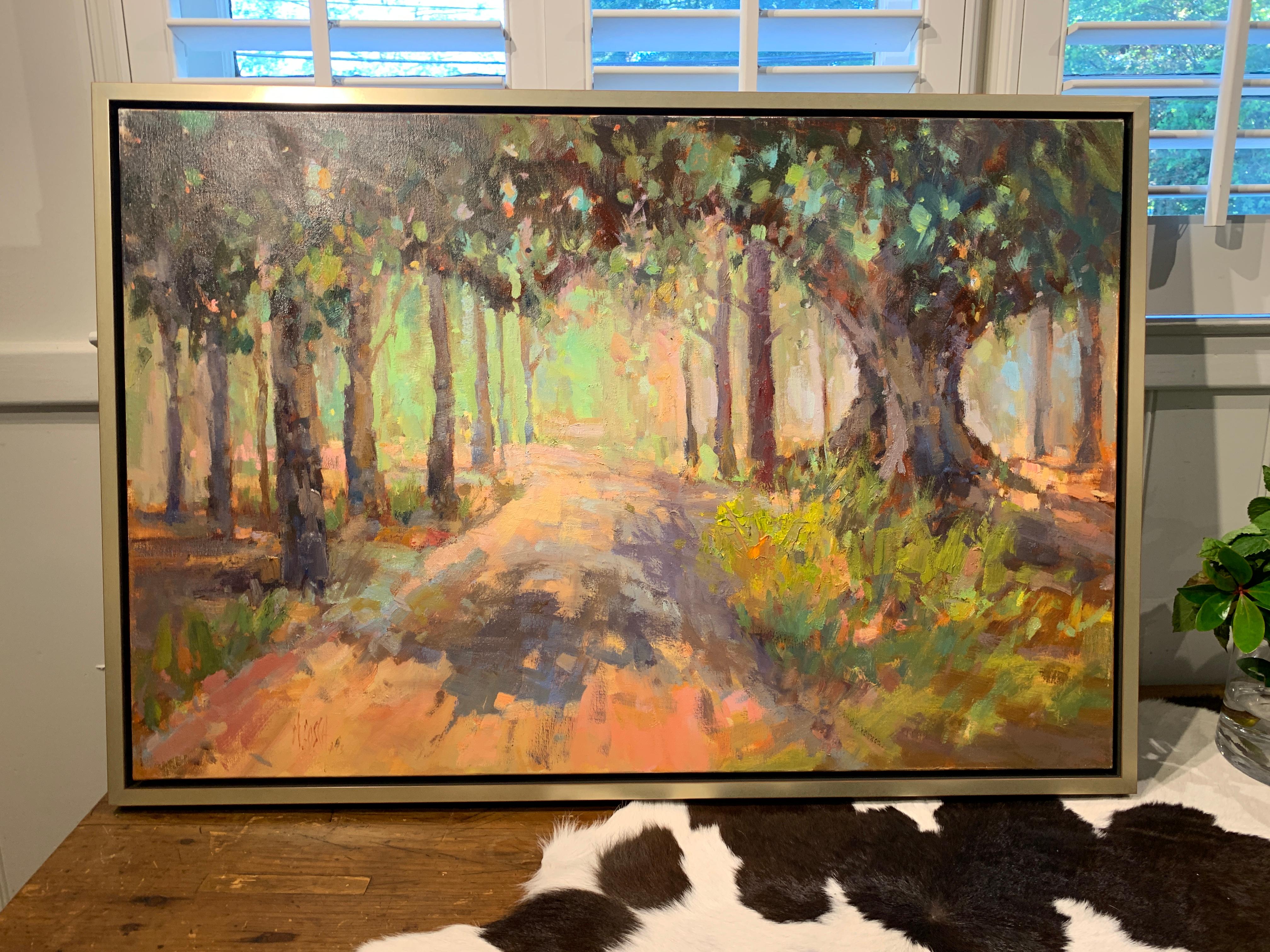 'Southern Pines' is a framed Impressionist oil on canvas plein-air landscape painting created by American artist Millie Gosch in 2019. Featuring a palette mostly made of green, brown, pink, purple, orange and blue tones, the painting depicts a dirt