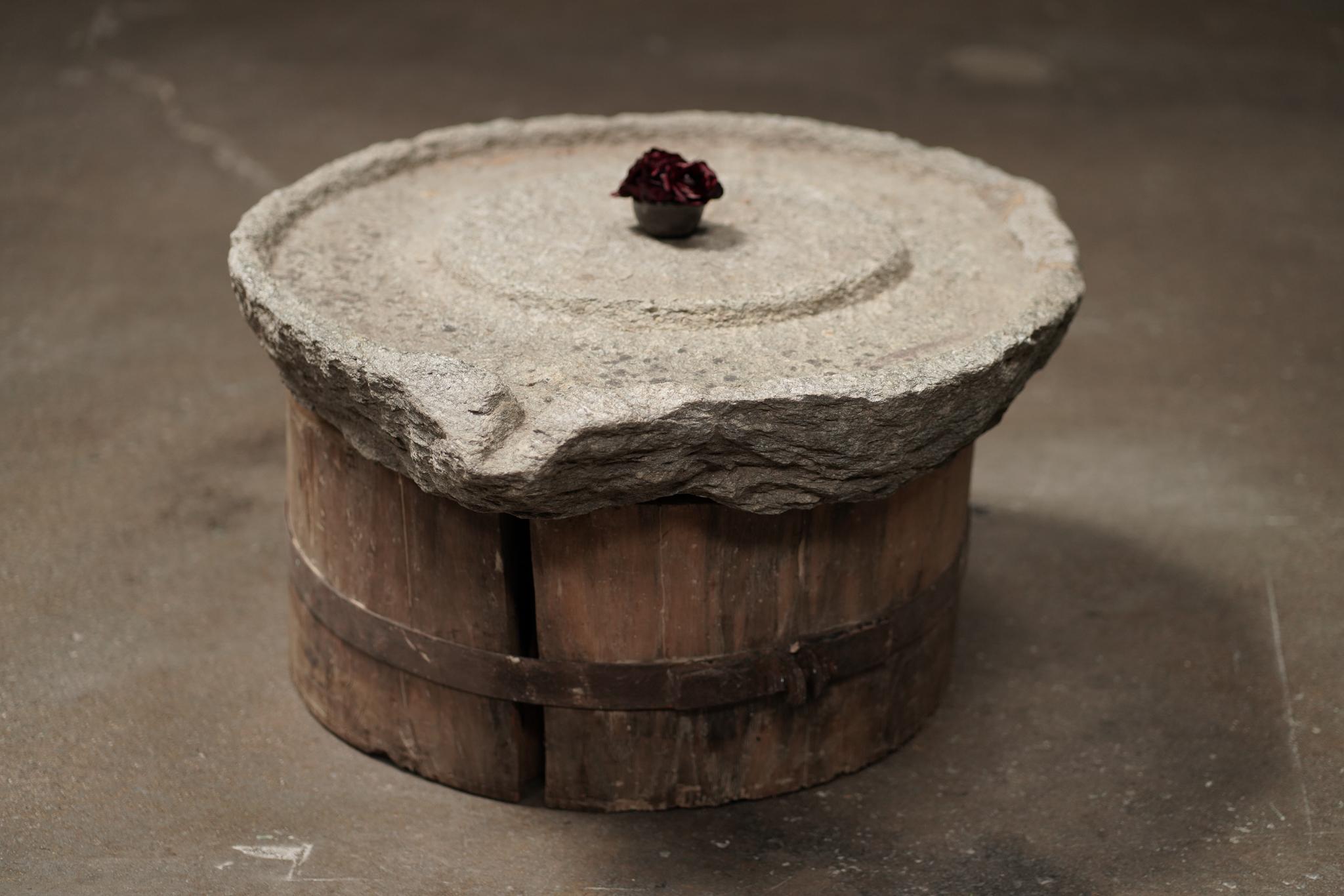 The Millstone Coffee Table features a hand-carved stone top set on an organic wood base, blending rustic texture with sculptural form. Sourced from Europe, its natural patina adds depth and character to this quietly commanding piece.