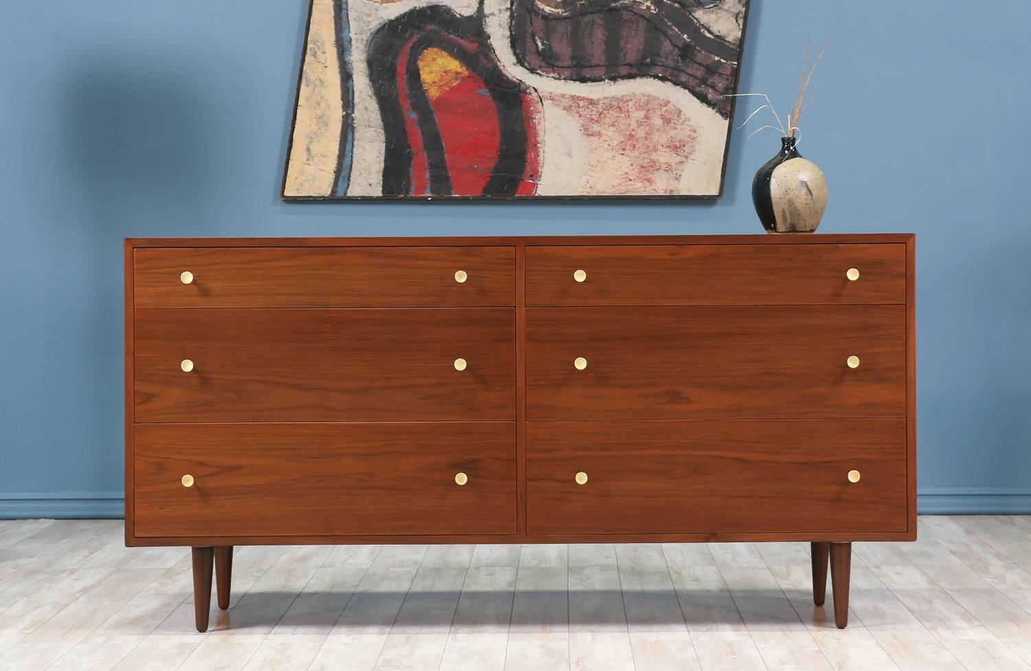Mid-Century Modern dresser designed by Milo Baughman for Glenn of California in the United States circa 1950’s. Supported by tapered legs, this newly refinished walnut wood dresser features six spacious dovetailed drawers adorned with polished brass