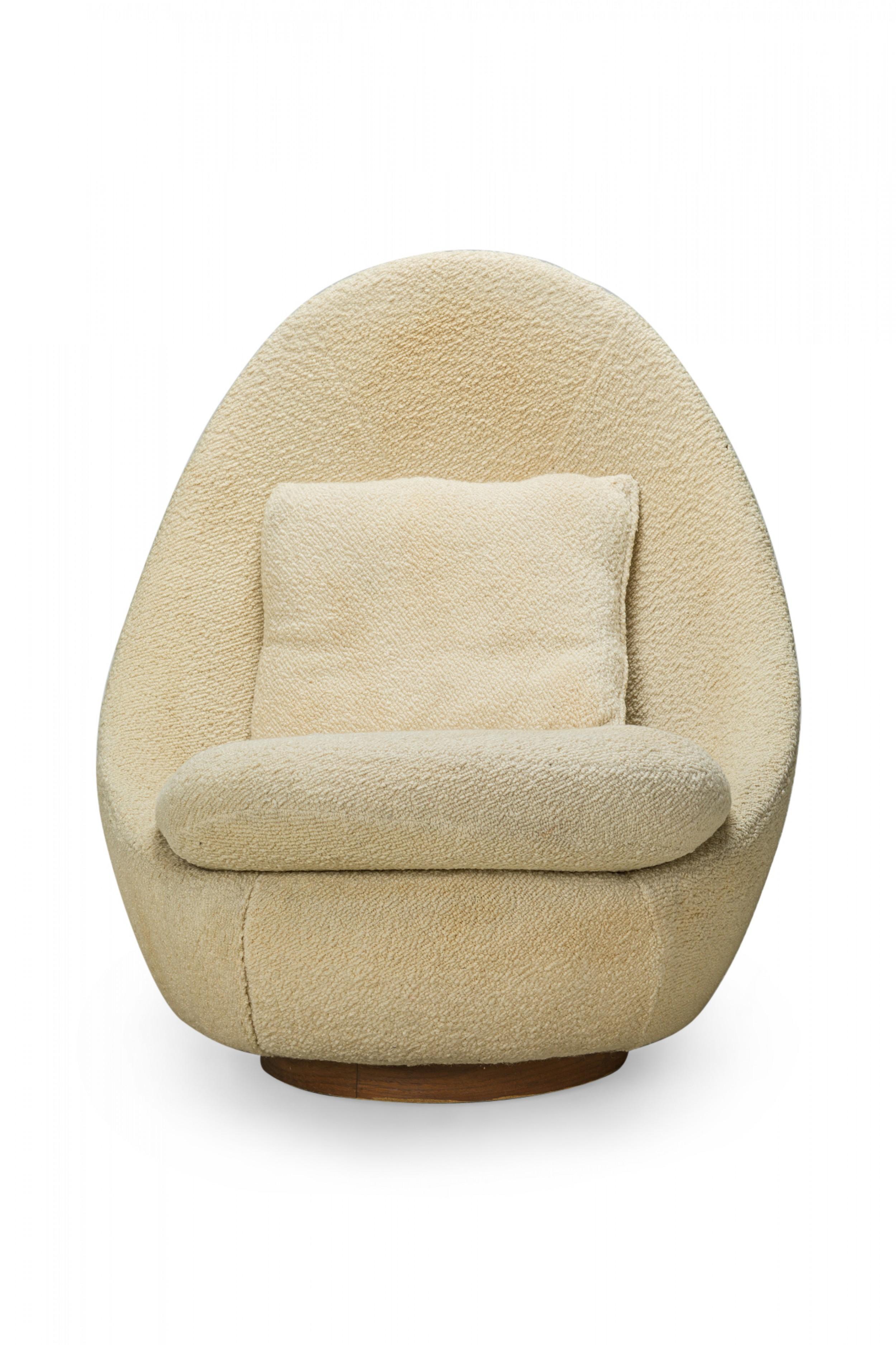 American Mid-Century swivel egg chair with a curved form upholstered in textured beige upholstery with a matching throw pillow. (MILO BAUGHMAN)(Available in other fabrics: DUF0341, DUF0343).
 