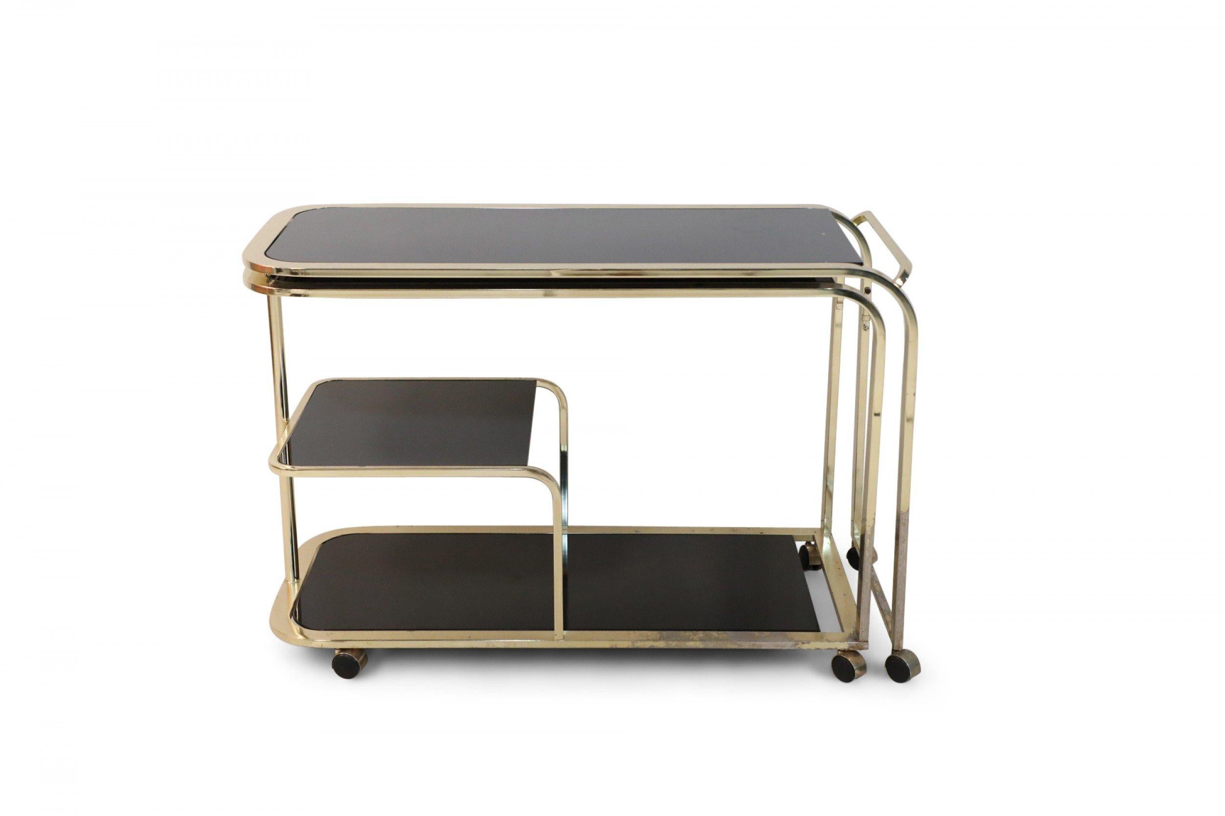 Mid-century American (circa 1970) two section brass frame bar cart with a pivoting two shelf bottom section that swivels out on casters with black glass shelves and surfaces. (width fully extended: 87