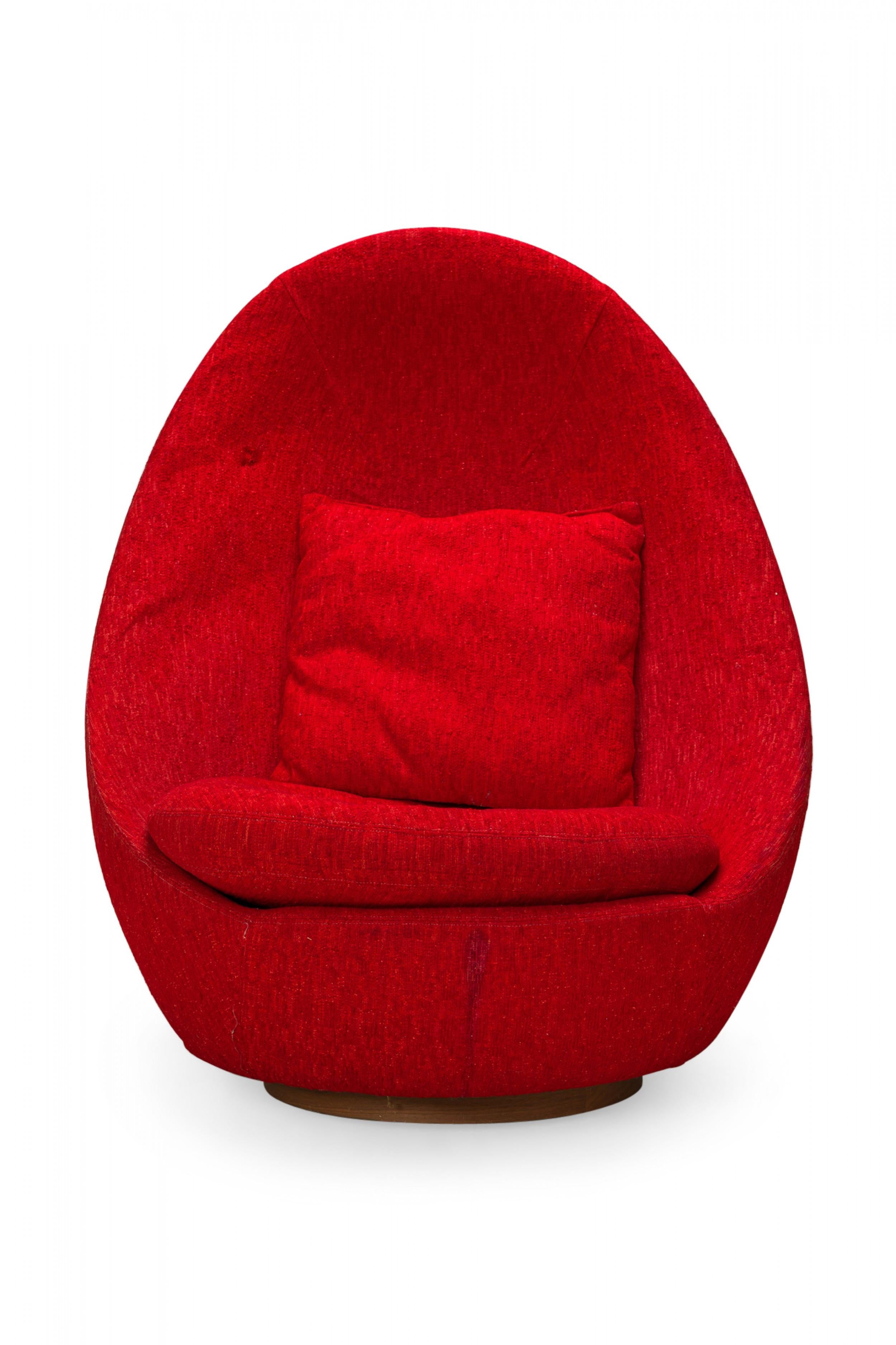 American Mid-Century swivel egg chair with a curved egg-like form upholstered in textured red upholstery with a matching throw pillow. (MILO BAUGHMAN)(Available in other fabrics: DUF0342, DUF0343)
