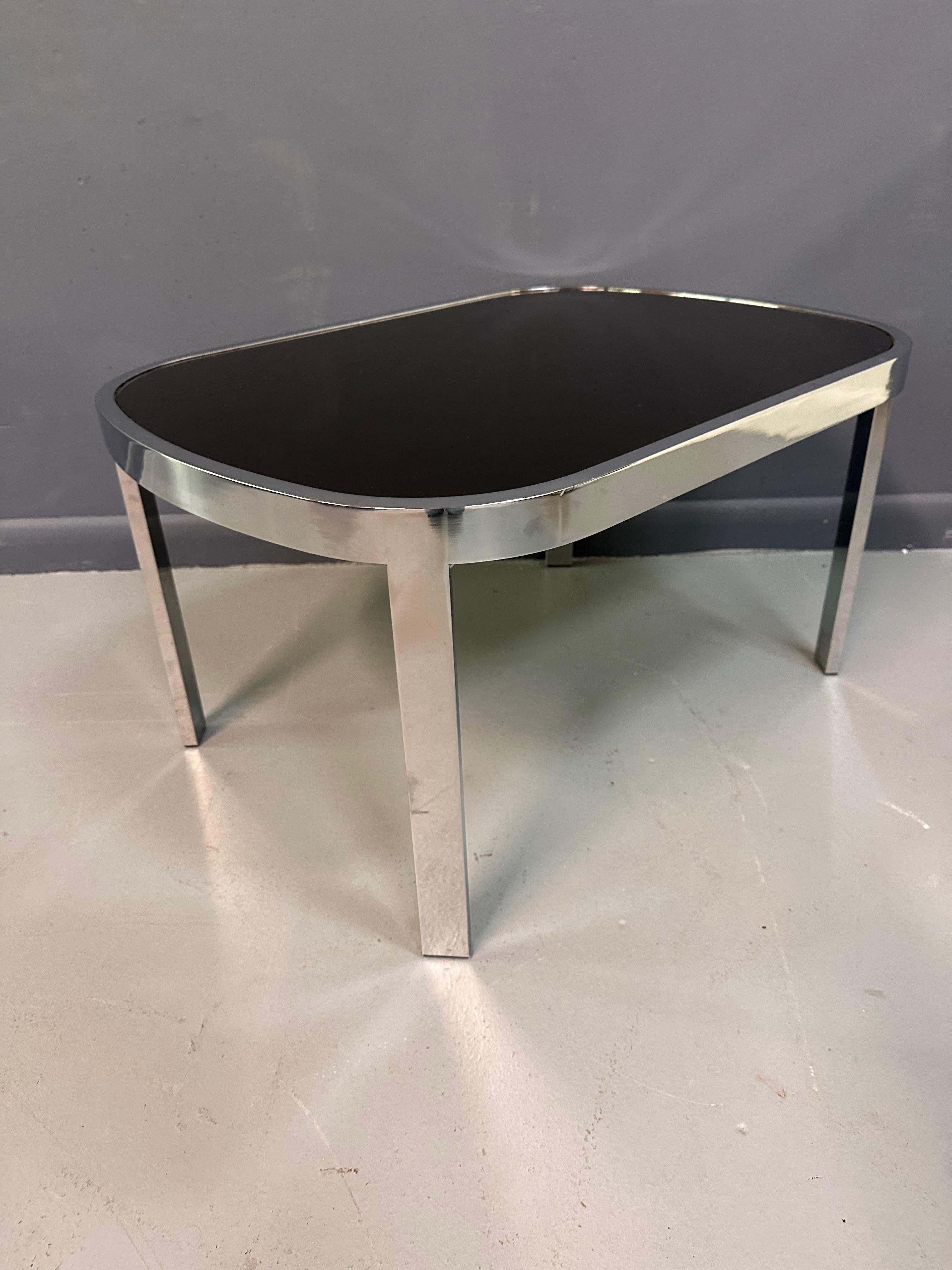 Sexy Milo Baughman side table in race track shape with a chrome frame and black glass insert. This side table will compliment many interiors but especially the mod 70s and 80s projects. This table looks like its moving fast just sitting there.