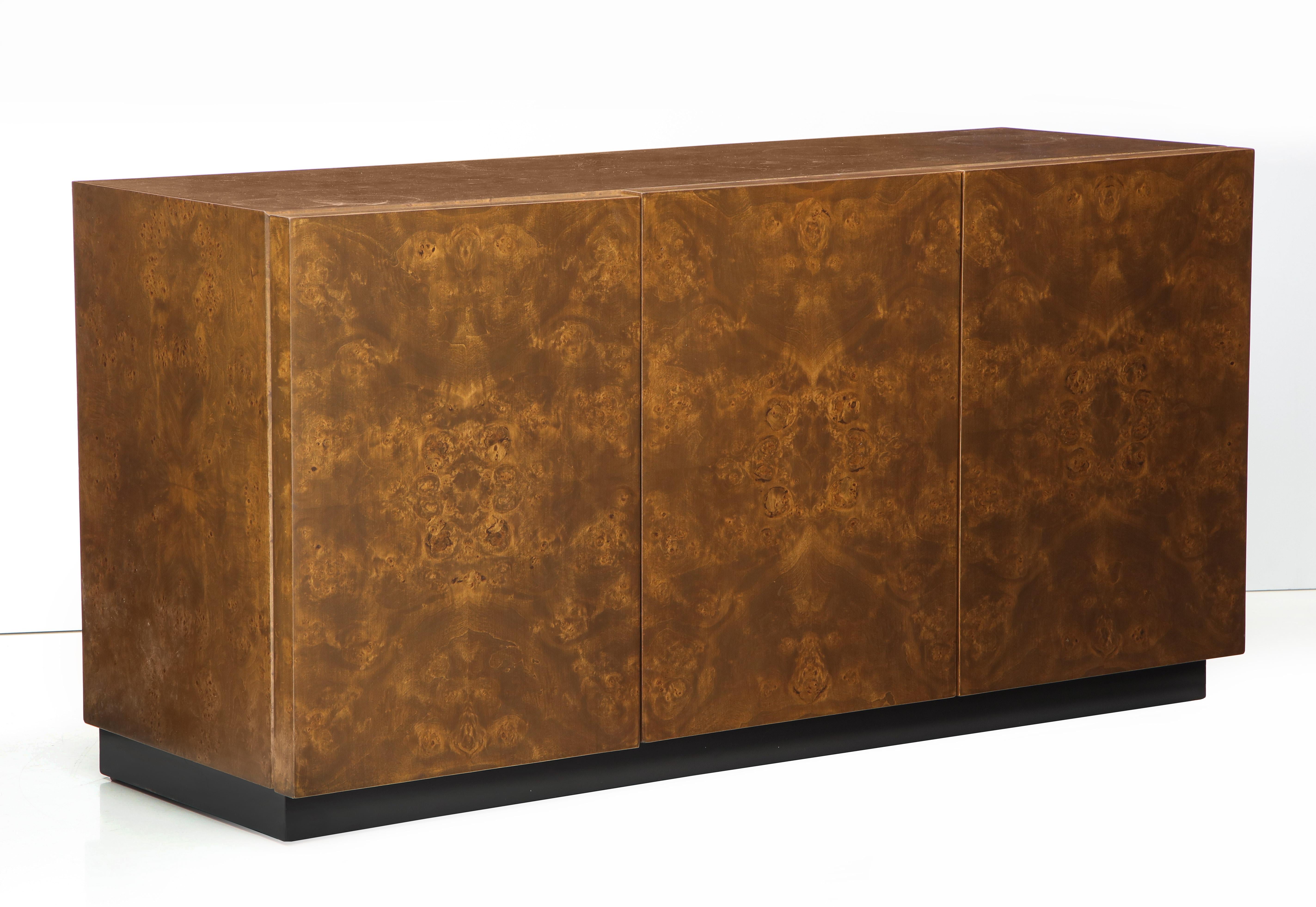 Magnificent 1970s Burl Walnut cabinet with 3 bookmatched front panels. 2 panels open to reveal 2 drawers and shelf, the other opens to compartment with adjustable shelf. Milo Baughman for Thayer Coogin. On display at 200 Lexington Avenue, 10th floor.