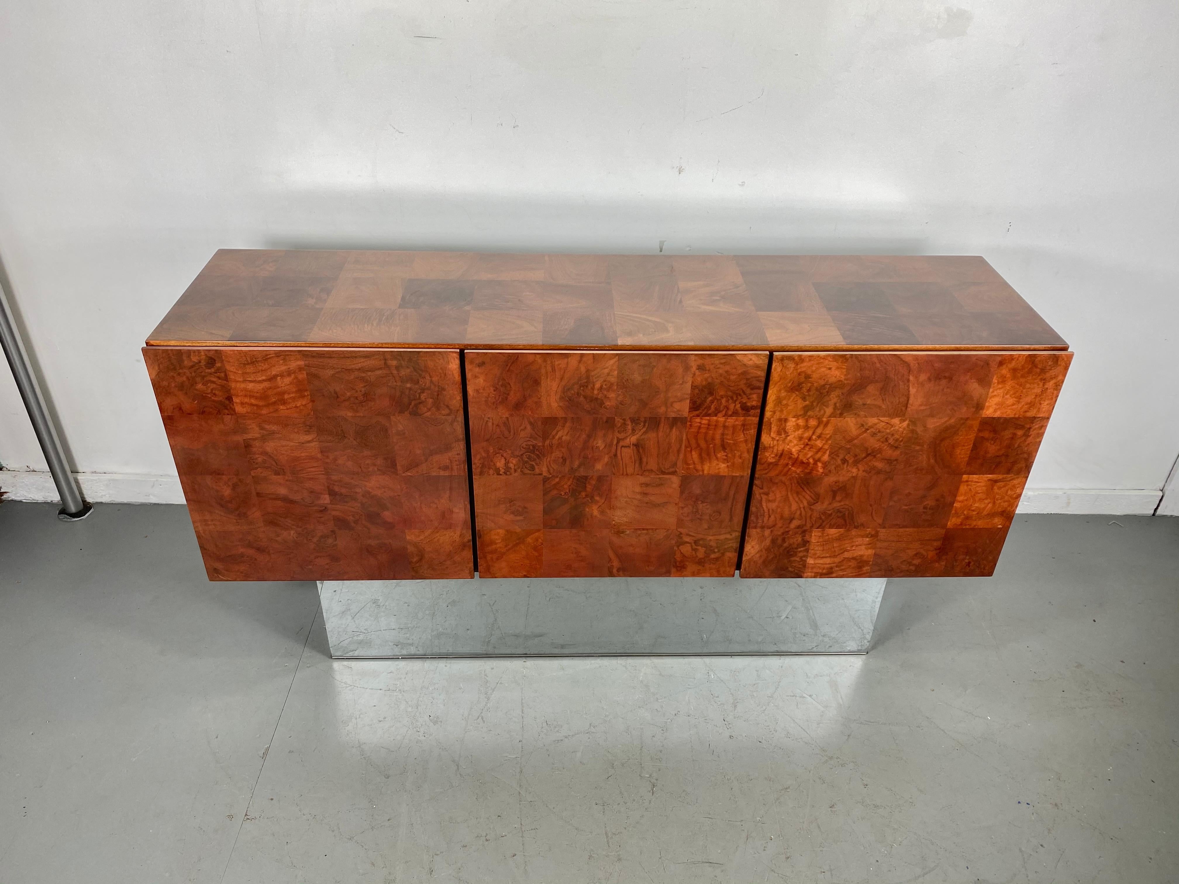 Gorgeous Milo Baughman tall burled patchwork walnut and chrome credenza. This piece retains its original finish and still looks amazing tall chrome plinth base has some minor dings hardly noticeable, two doors with shelf, left door with four white