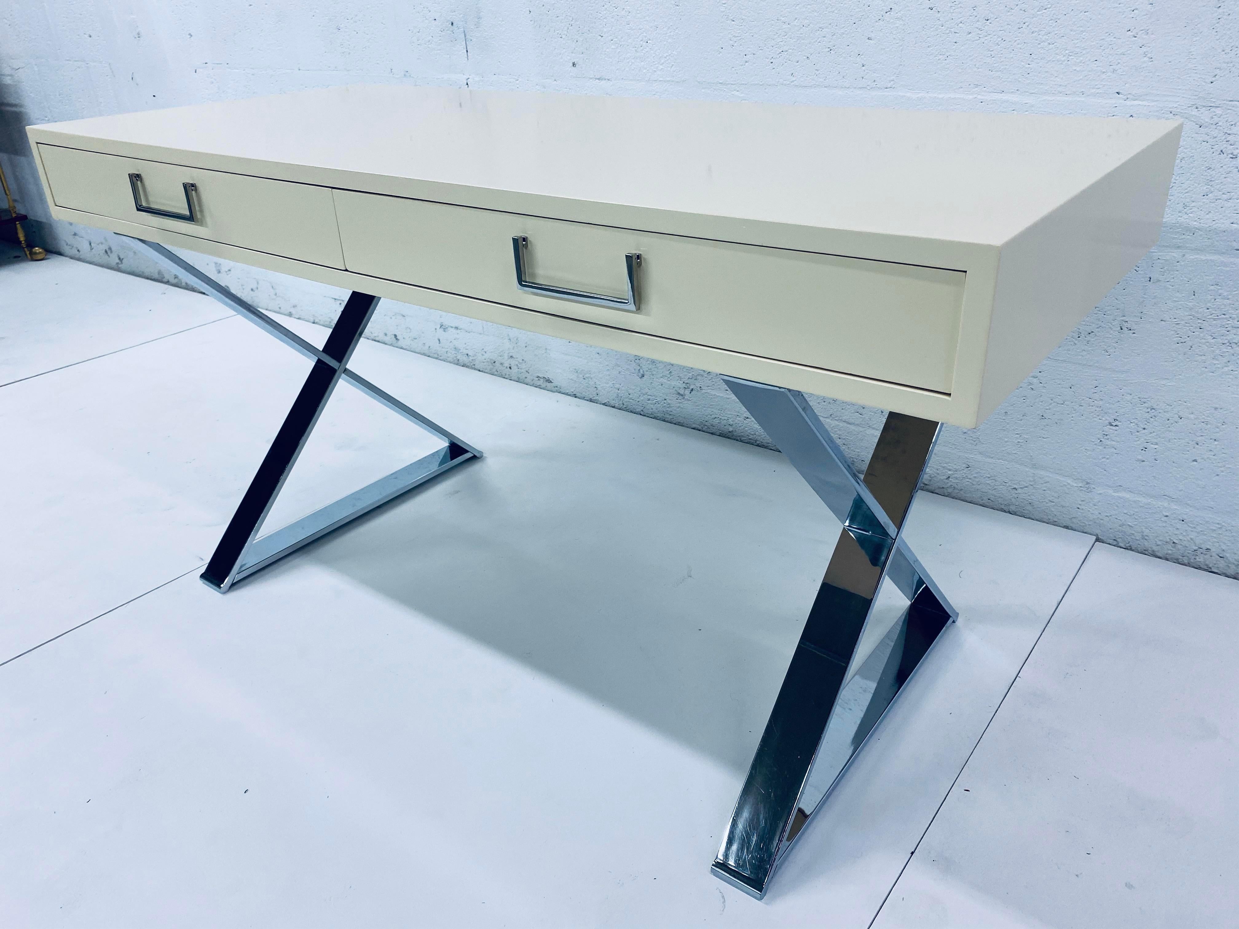 Lacquered antique white West Michigan Furniture Campaign desk for John Stuart. Writing desk sits on two chrome X frames and contains two large drawers with hinged chrome pulls. This piece has been expertly restored with a new lacquer finish and the