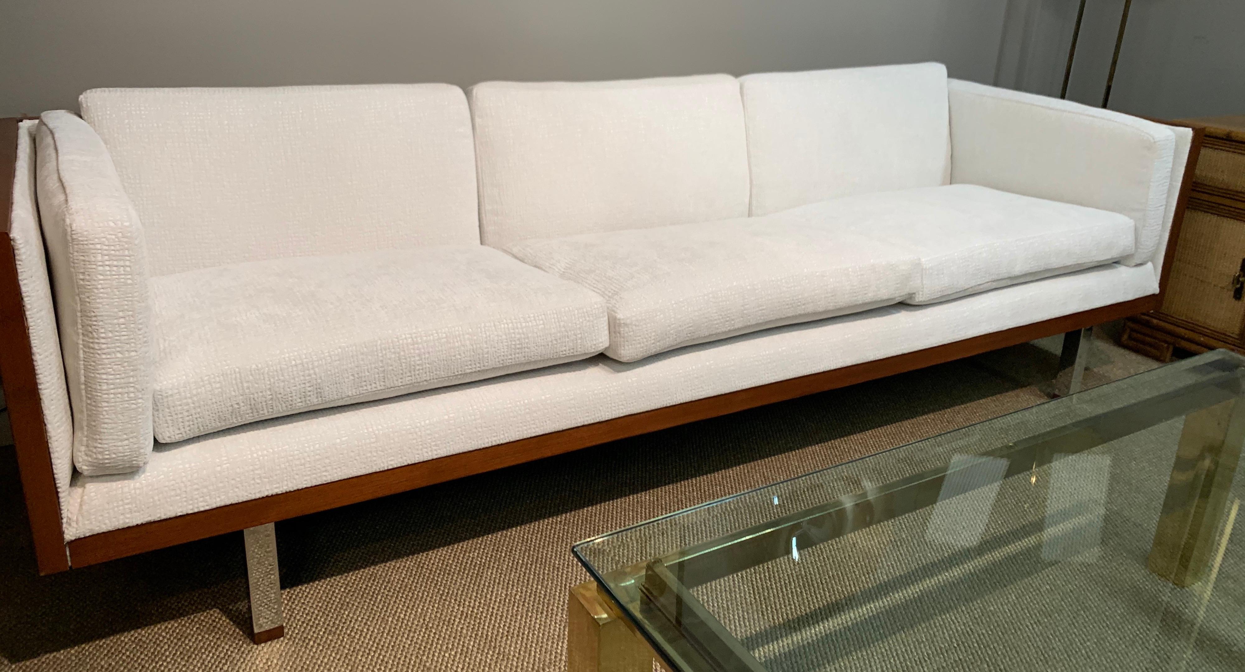 Newly upholstered in an off white cream subtle chenille fabric and with iconic design lines, this three-seat sofa encased in walnut is a must have. It is supported by chrome feet. Now, more than ever, home is where the heart is. 
  