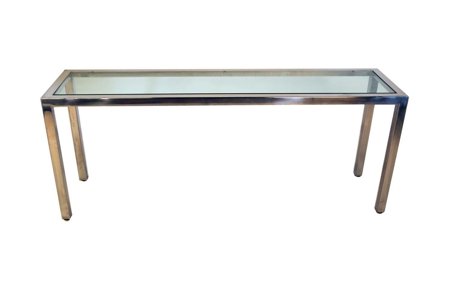 A lovely, midcentury, polished chrome, console or sofa table, with glass insert by Milo Baughman. Features a thick sturdy frame, in a lovely shiny chrome mirrored finish. Has an inlay of thick rectangular glass, that flows down to an inset of a