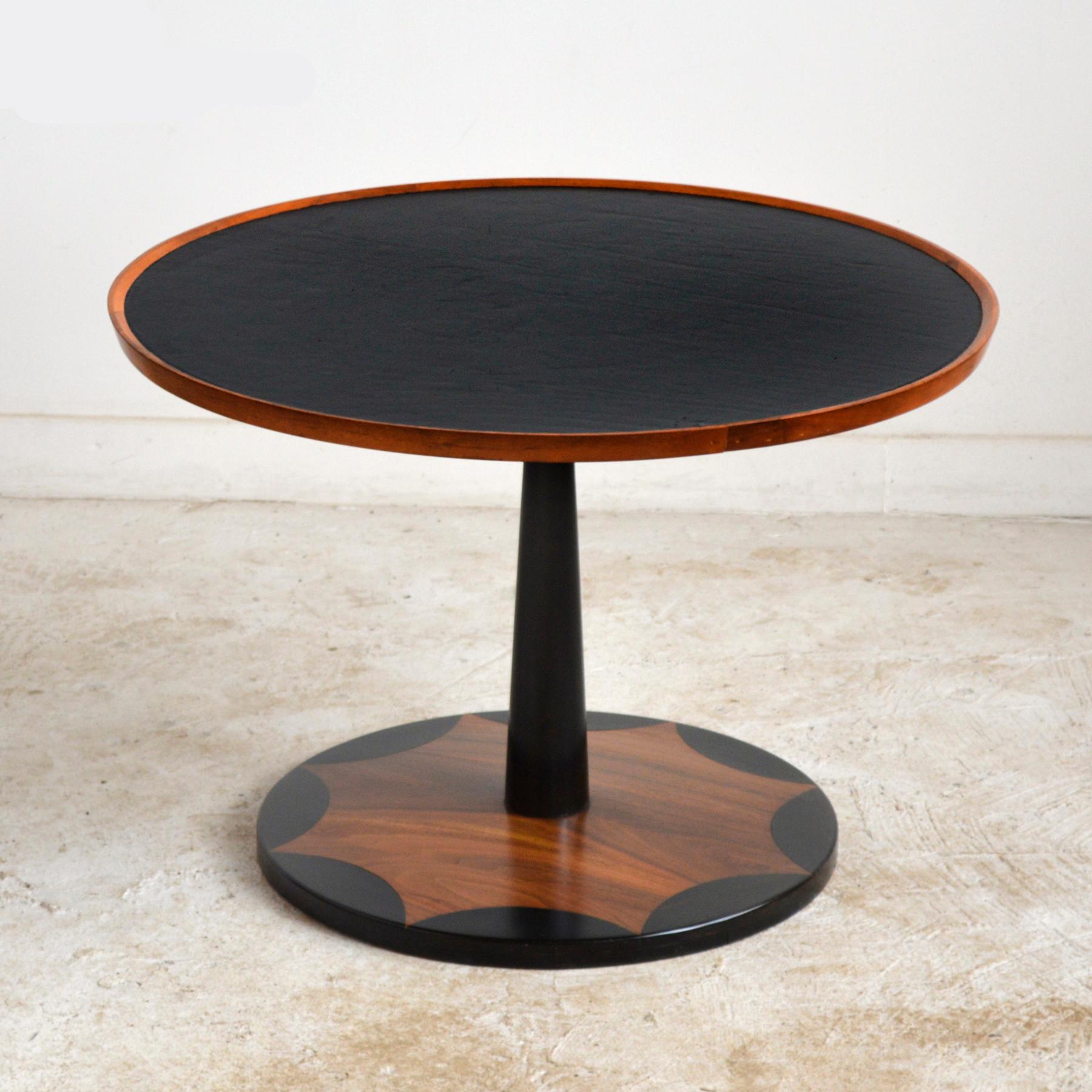 This wonderful early walnut table by Milo Baughman table by Arch Gordon has an ebony-inlaid base that supports an elegantly tapered black post which supports a top with a leather surface surrounded by a raised pie crust edge. The terrific scale