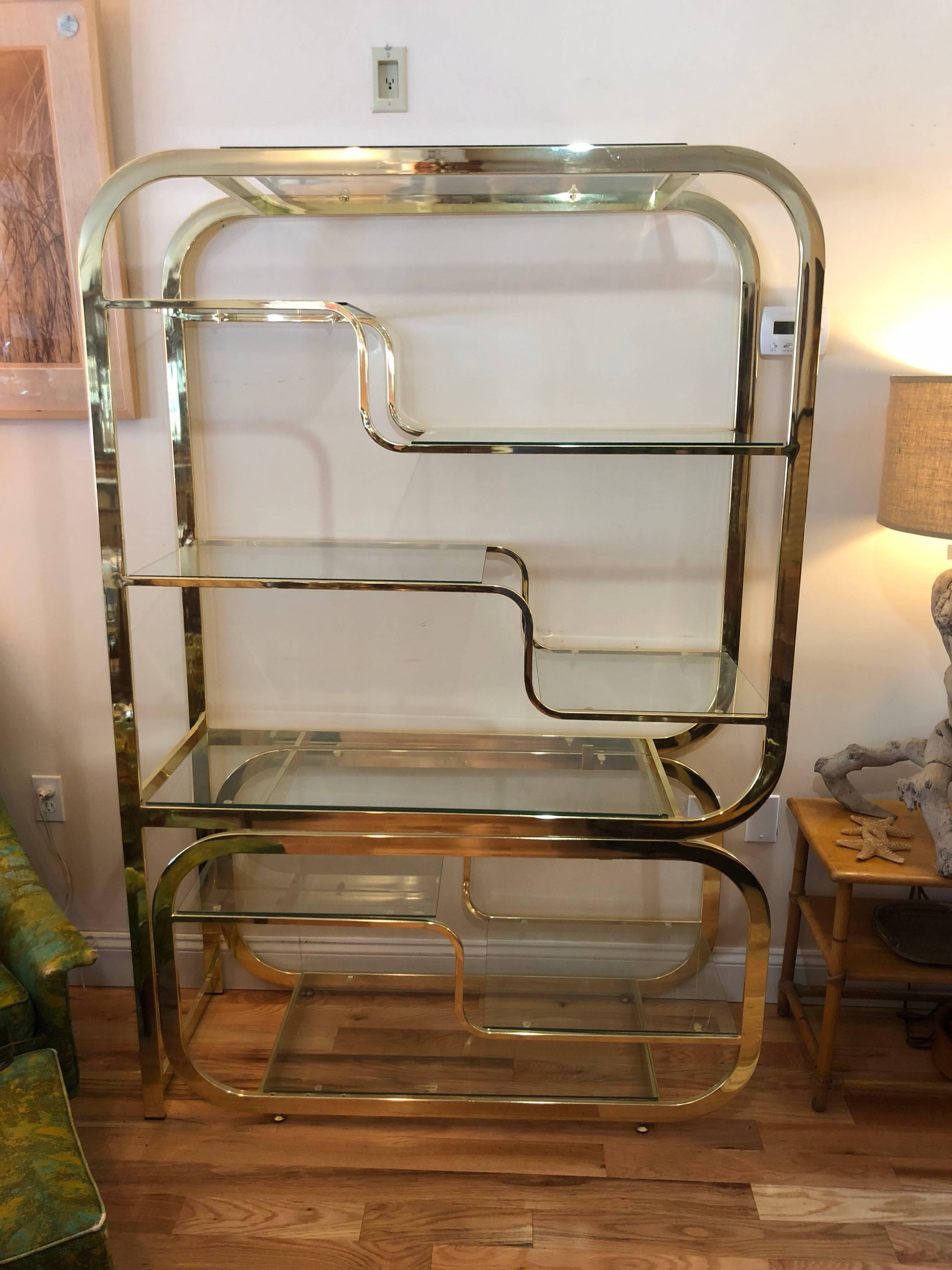 Milo Baughman DIA style brass and glass étagère. Fabulous Hollywood Regency focal piece. With polished brass. Some of the existing glass shelves are not fitted properly. We will have them cut to exact dimensions so that they fit perfectly. You can