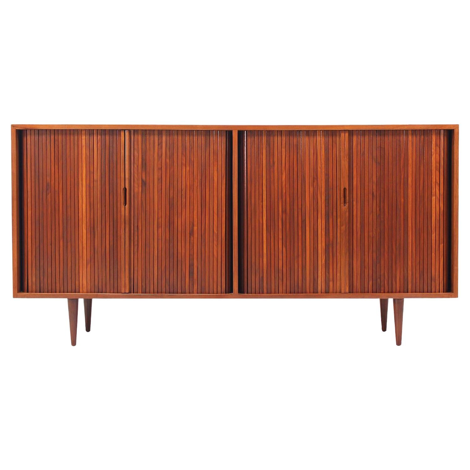 Mid-Century Modern credenza designed by Milo Baughman for Glenn of California in the United States circa 1950s. Crafted in walnut wood, this exceptional credenza features two compartments, each with its set of tambour doors and carved, recessed