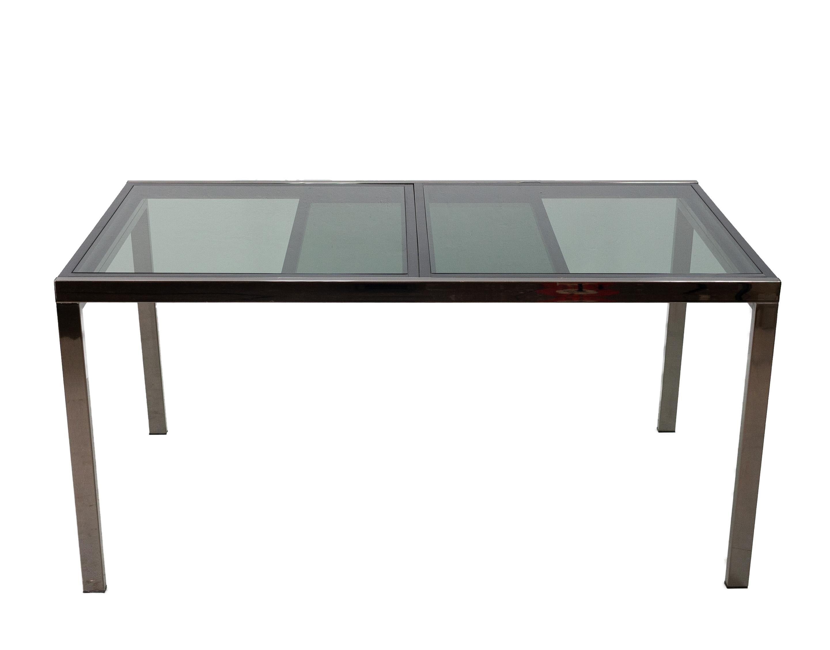 Vintage extendable dining table in grey smoked glass, circa 1970s. The table can be increased from 155 cm to 227 cm. One off the first editions off this table, comes width a black ebonized wooden frame, witch hold the grey smoked glass, the steel