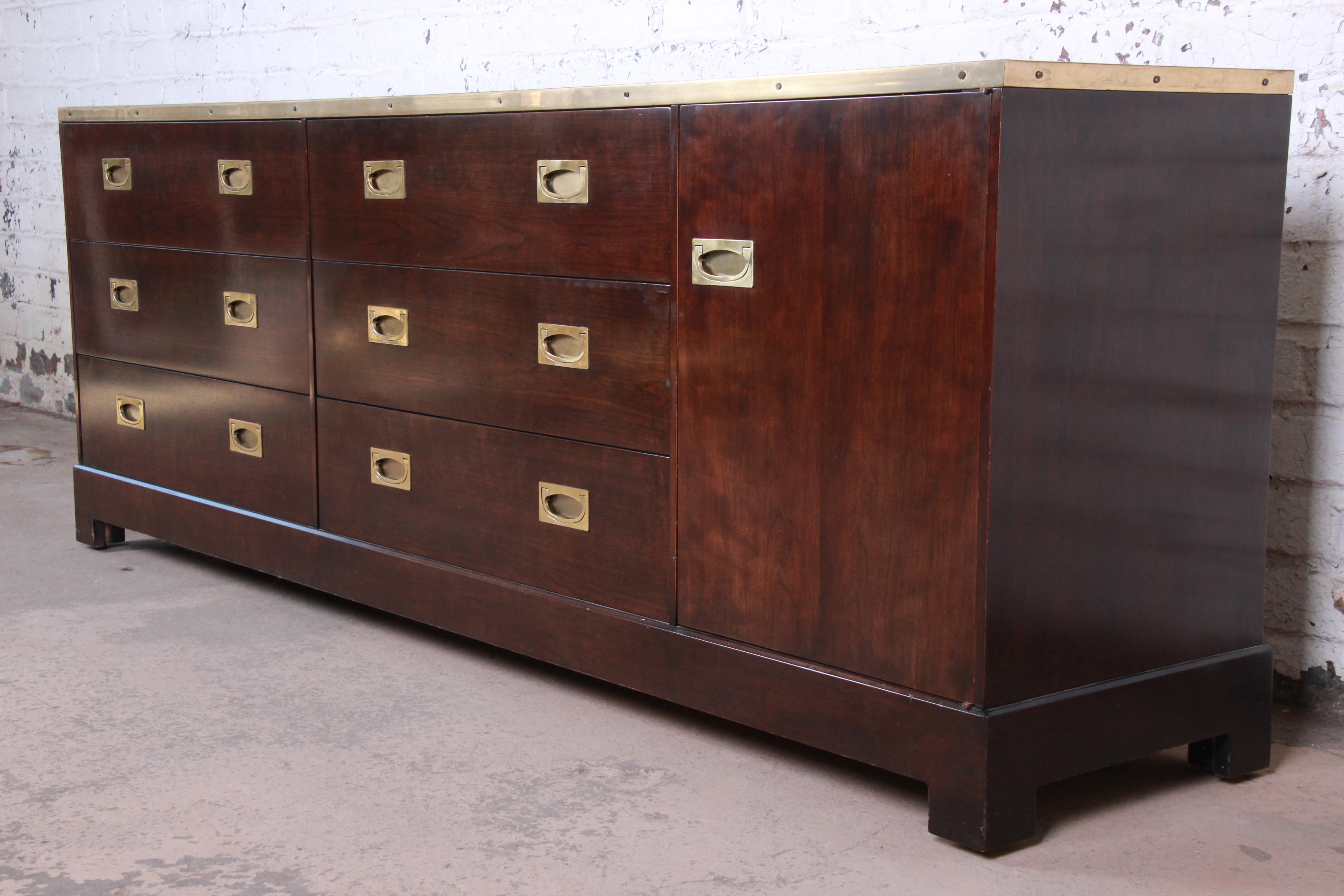 An exceptional Mid-Century Modern Hollywood Regency Campaign style triple dresser or credenza by Milo Baughman for the exclusive Custom collection for Directional. The credenza features rich wood grain with elegant brass trim and original brass