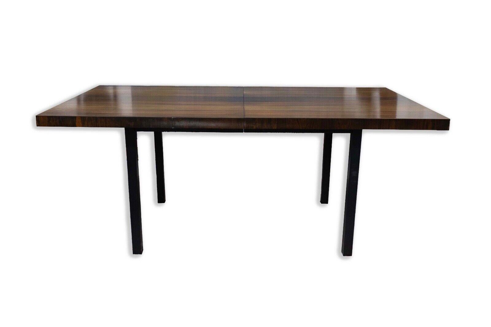 The Milo Baughman for Directional Expandable Dining Table is a stunning embodiment of mid-century modern design, showcasing the timeless elegance of this era. Crafted with a masterful combination of teak, rosewood, and walnut wood, it exudes a rich