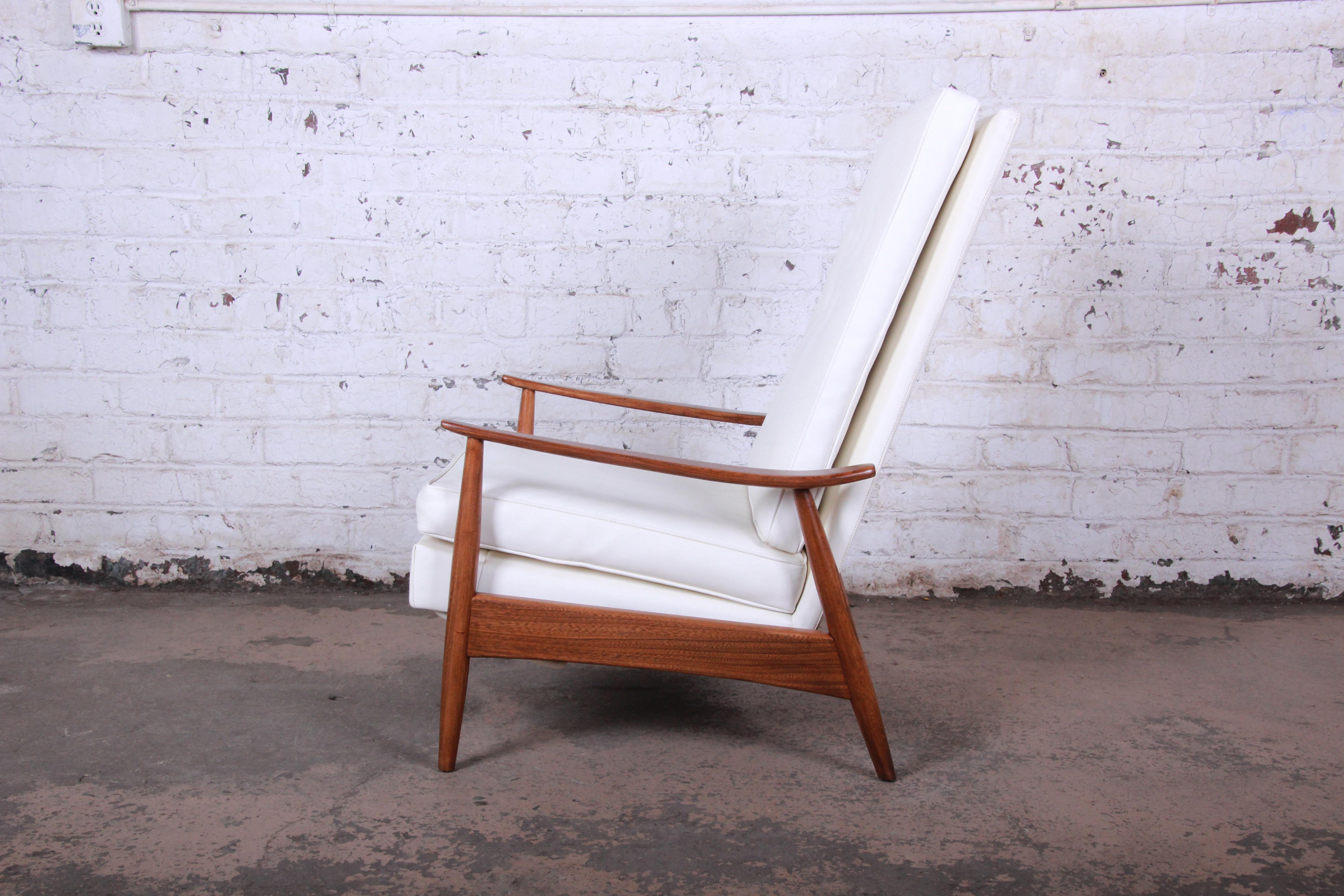 An exceptional Mid-Century Modern reclining lounge chair designed by Milo Baughman for James Inc. The chair features a gorgeous sculptural walnut frame and original white vinyl upholstery in excellent condition. The frame has been professionally