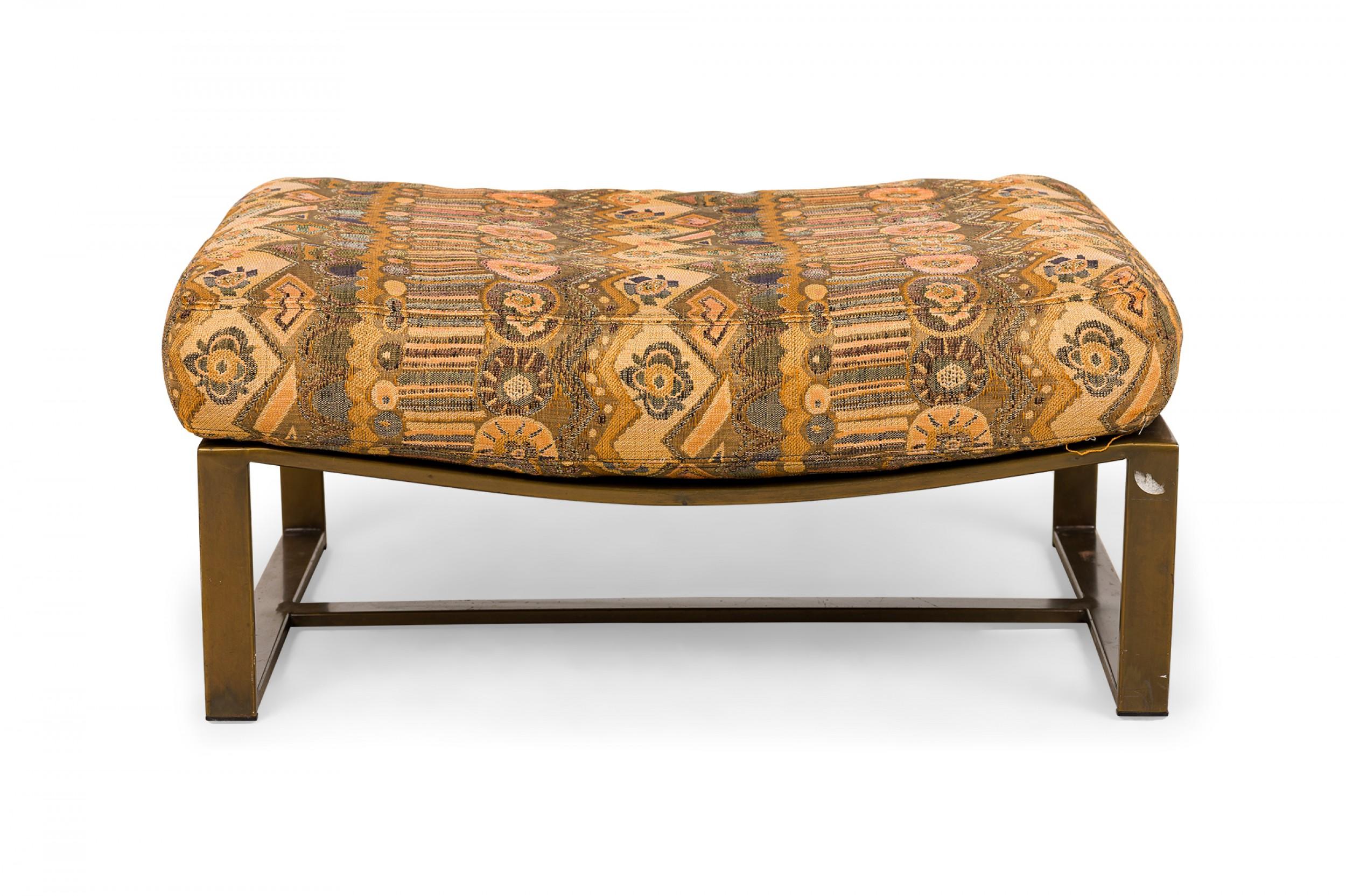 American Mid-Century rectangular ottoman with a top upholstered in an intricately patterned beige and brown fabric, resting on rectangular walnut legs with a stretcher base. (MILO BAUGHMAN FOR THAYER COGGIN)