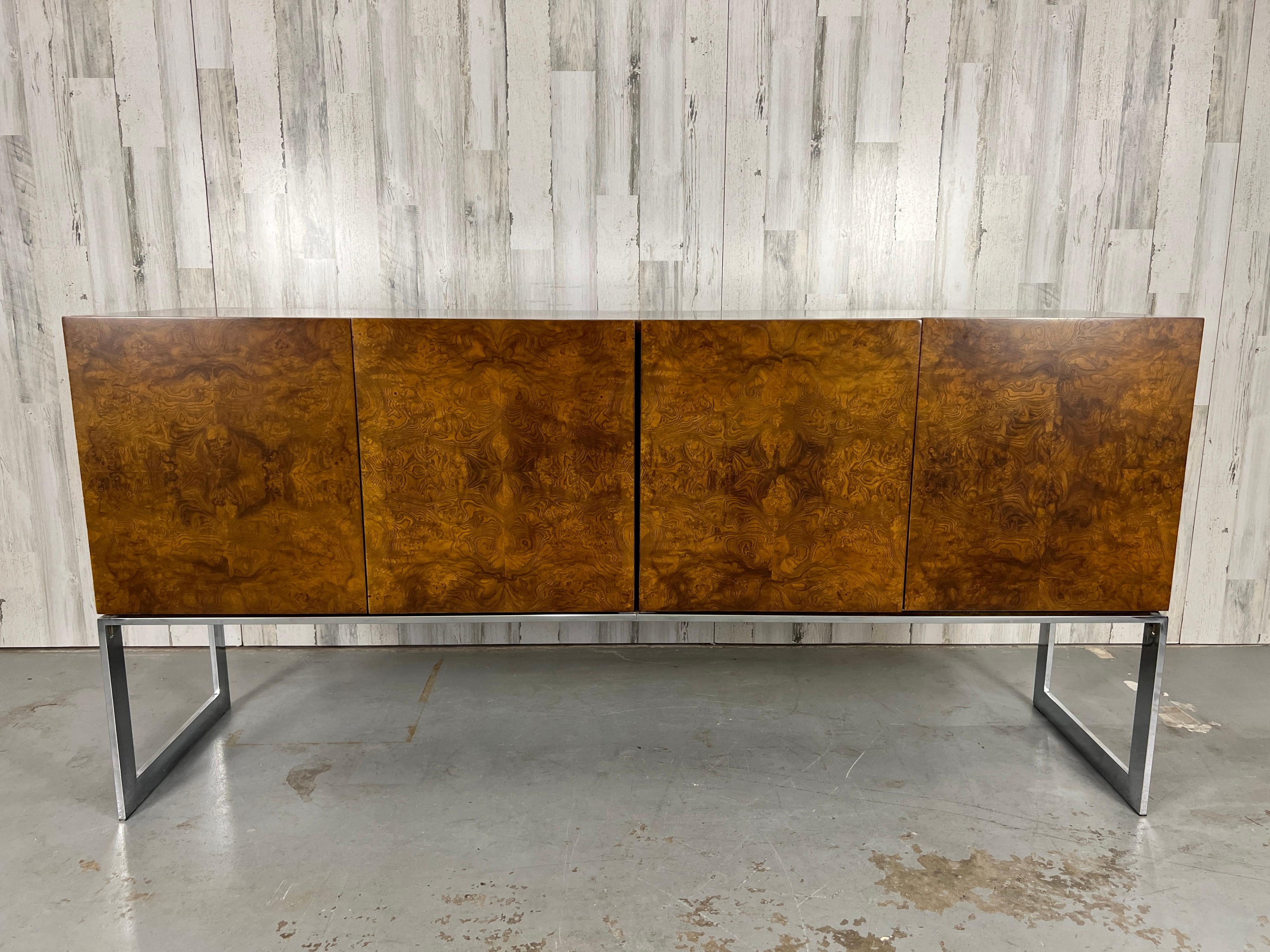 Burl wood covered credenza a top sturdy chrome legs that give this the appearance of floating above the floor. Interior has all the original drawers and shelves including one smoked glass shelf. Drawers still retain the original burnt orange velvet