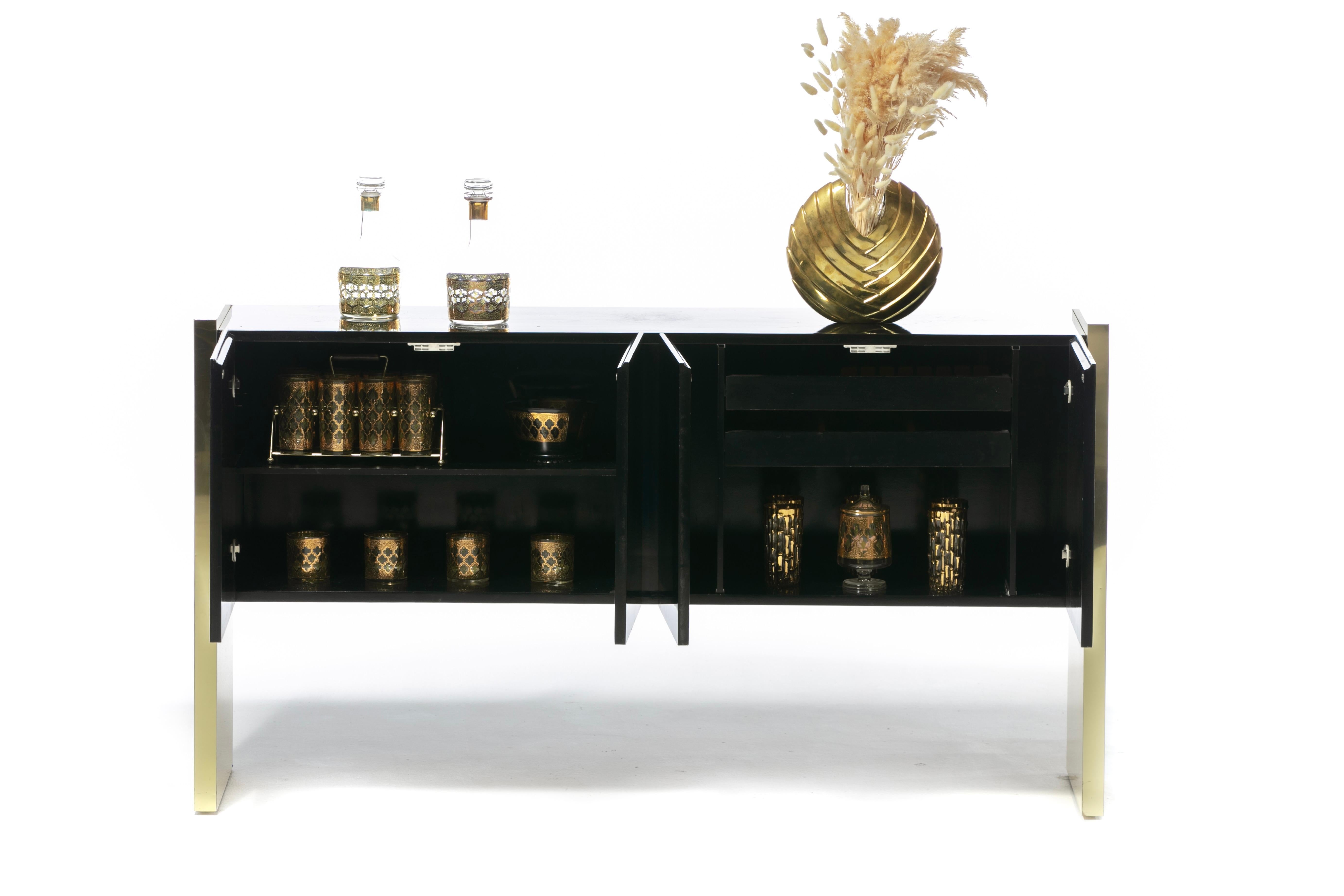 Sleek Milo Baughman black lacquered credenza or sideboard with tall brass slab legs made by Thayer Coggin in the 1970s. Elegant Modern profile. The look is powerful and upscale. Black lacquered cabinet seems to float between two large rectangular