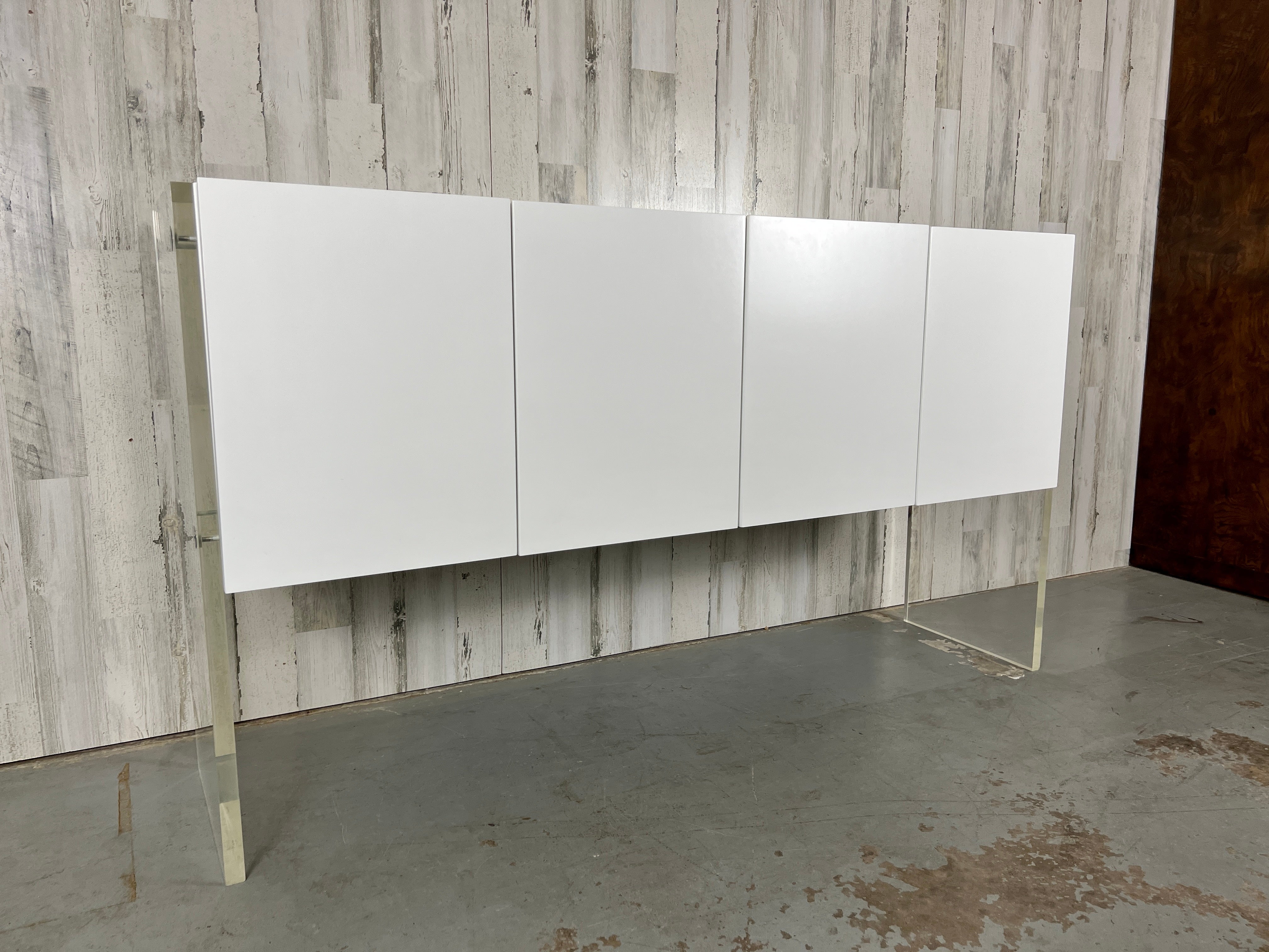 Milo Baughman for Thayer Coggin Lacquer and Lucite credenza. Refinished in pure satin white lacquer, held up by transparent lucite legs that create a floating illusion.