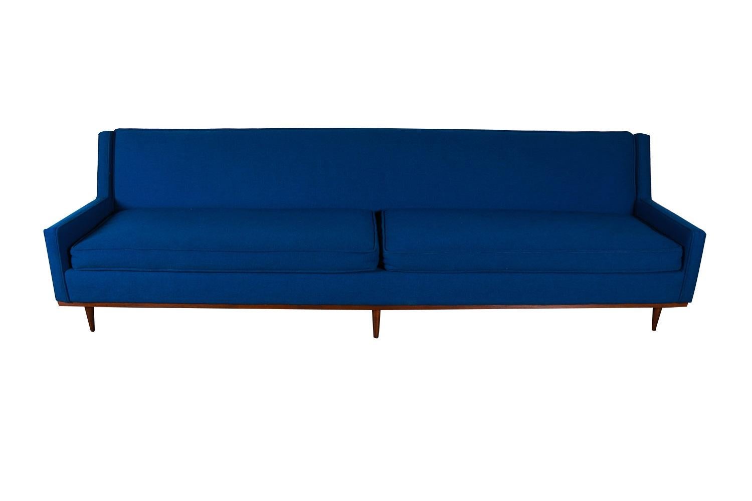 A very attractive two-seater sofa. Distinctive early mid century modern design shows Danish influence. Features original electric cobalt blue upholstery, two removable zippered seat cushions that are well intact. The tight back and clean modern