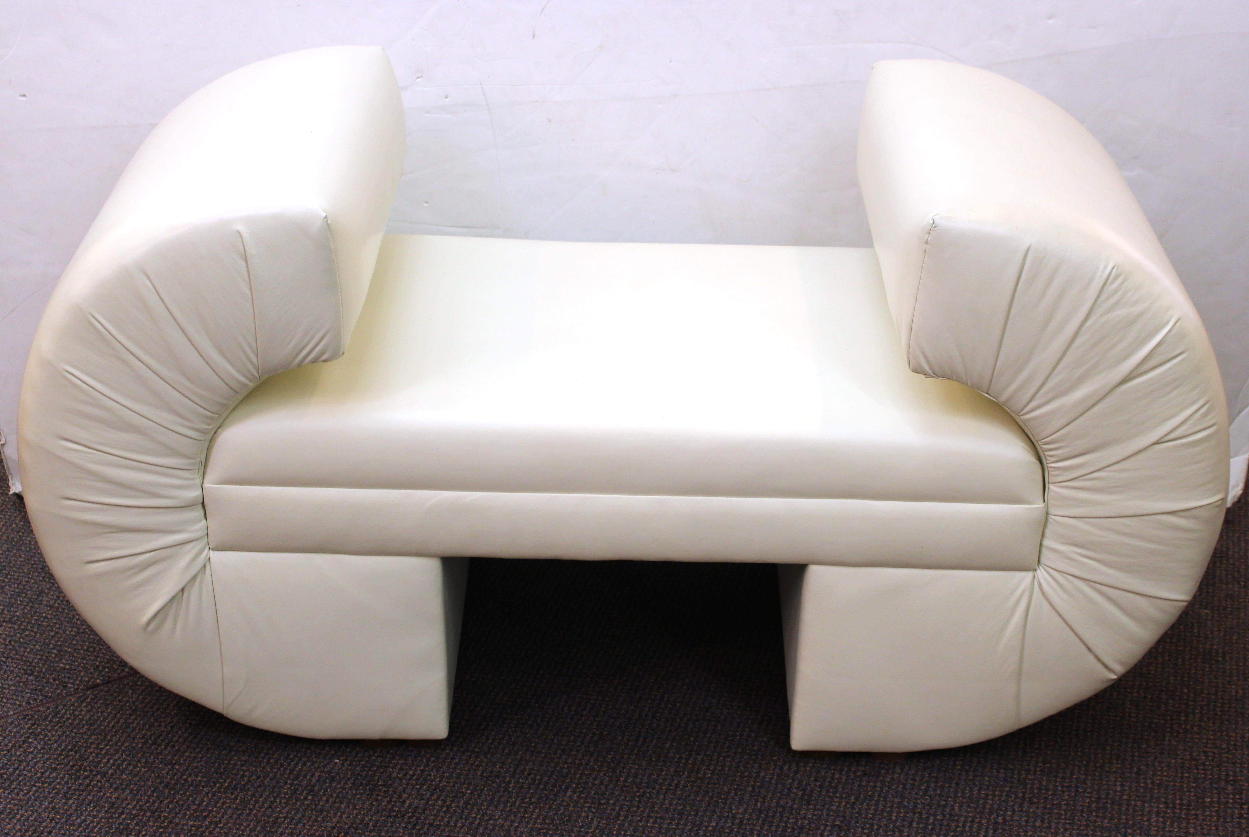 Post-modern white leatherette bench designed by Milo Baughman for celebrated American manufacturer Thayer Coggin. The piece has swung armrests holding up the seating surface and the faux leather has very minor age-appropriate wear. In great vintage