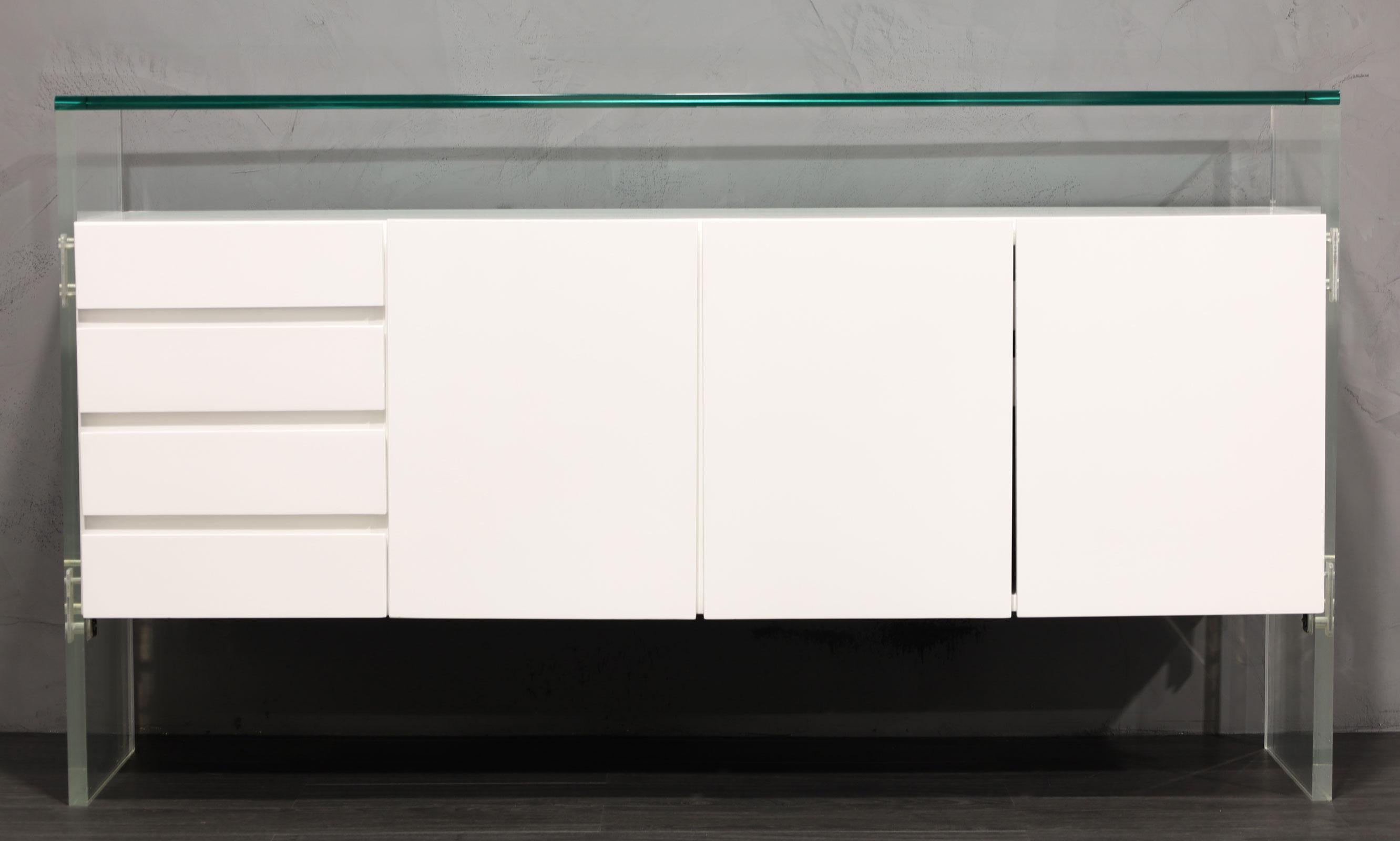 One of his iconic designs, a restored in white lacquer sideboard by Milo Baughman. Sideboard features a floating case piece that includes three doors with shelving and silverware storage. On the left side is four drawers. The thick Lucite legs