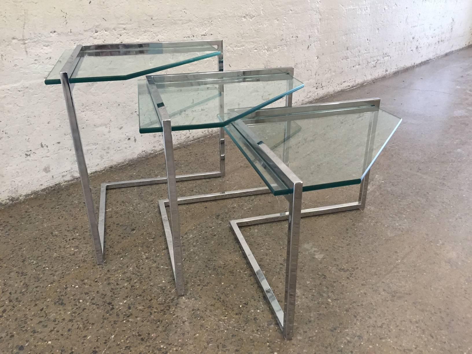 Tables gigognes chromées style Milo Baughman.  Les tables ont des plateaux en verre triangulaires avec un joli cadre chromé.  
La table la plus grande mesure : 22.25