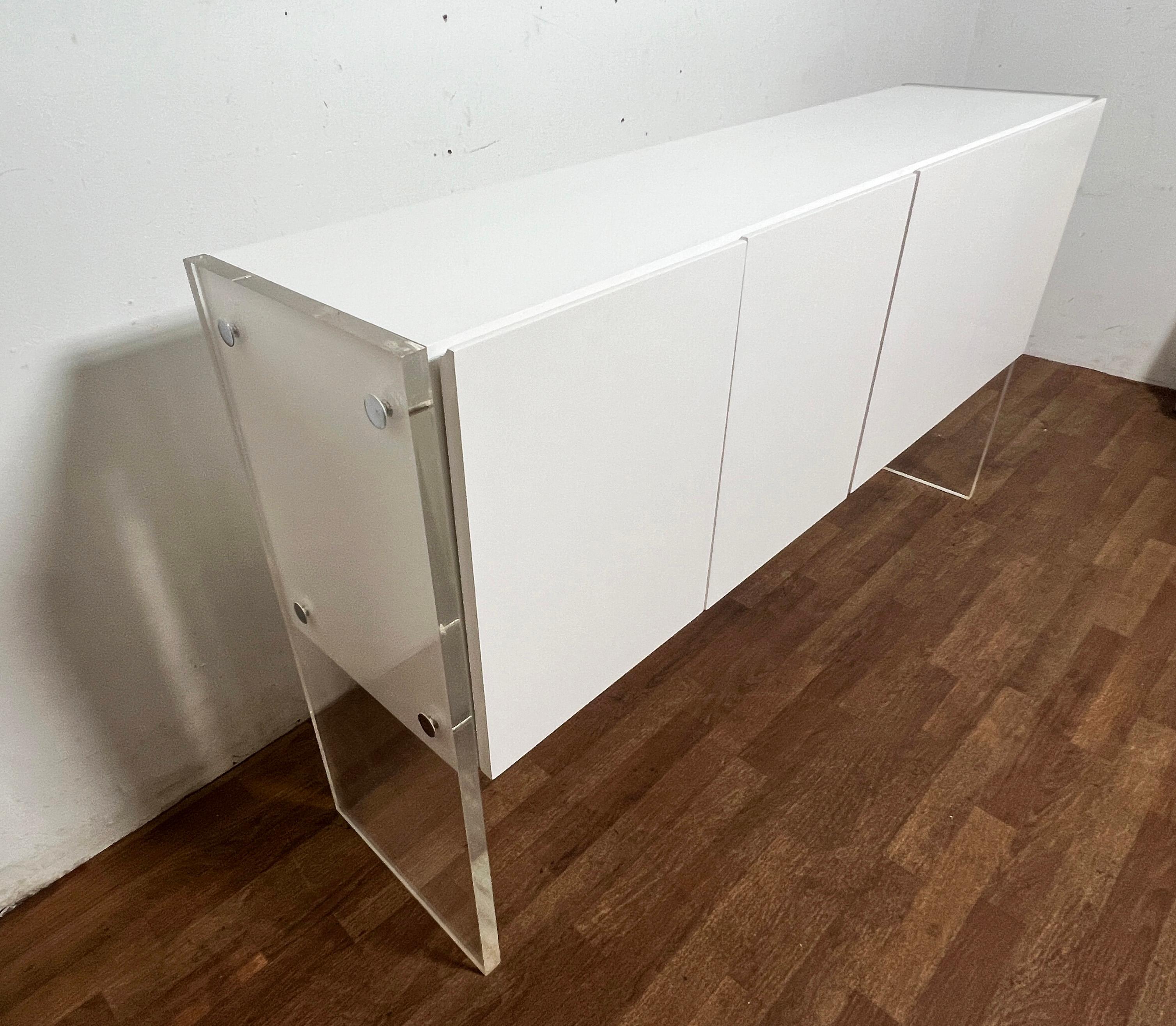 White lacquered four door credenza with lucite side panels by Milo Baughman for Thayer Coggin, circa 1970s. Includes ample storage space including a smoked glass bottle shelf.