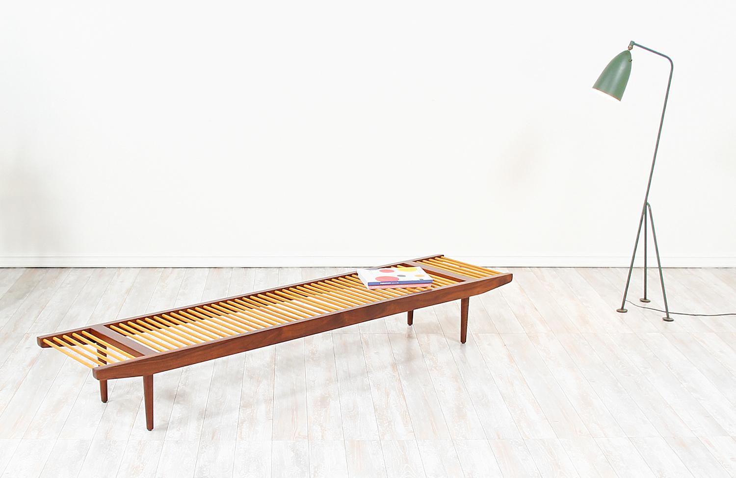 Elegant Californian Modern bench designed by Milo Baughman for Glenn of California in the United States, circa 1950s. This beautiful large dowel bench features a solid low profile frame and is comprised of a lovely contrast of walnut wood and