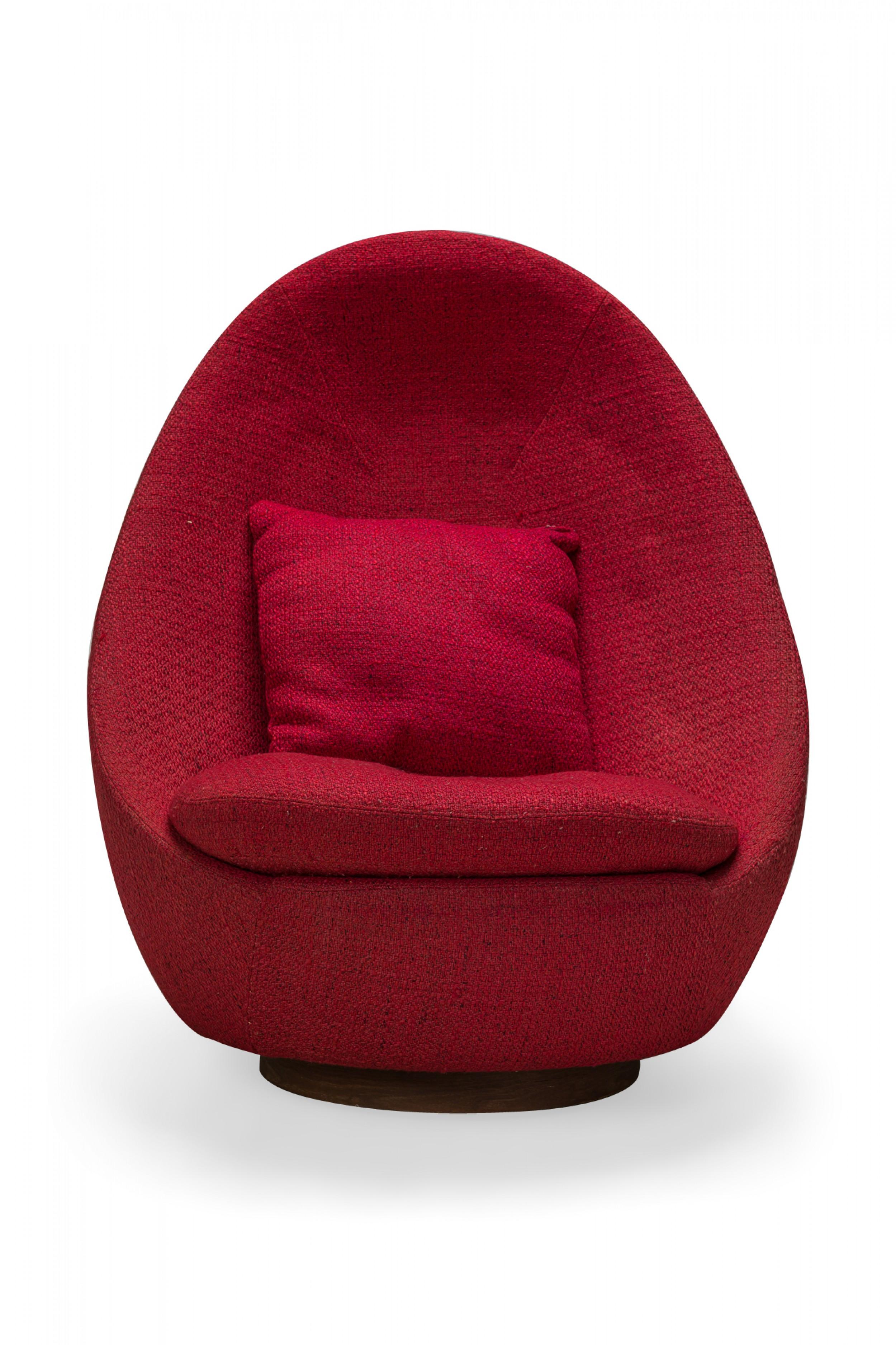 American Mid-Century swivel egg chair with a curved form upholstered in textured light red upholstery with a matching throw pillow. (MILO BAUGHMAN)(Available in other fabrics: DUF0341, DUF0342).
 