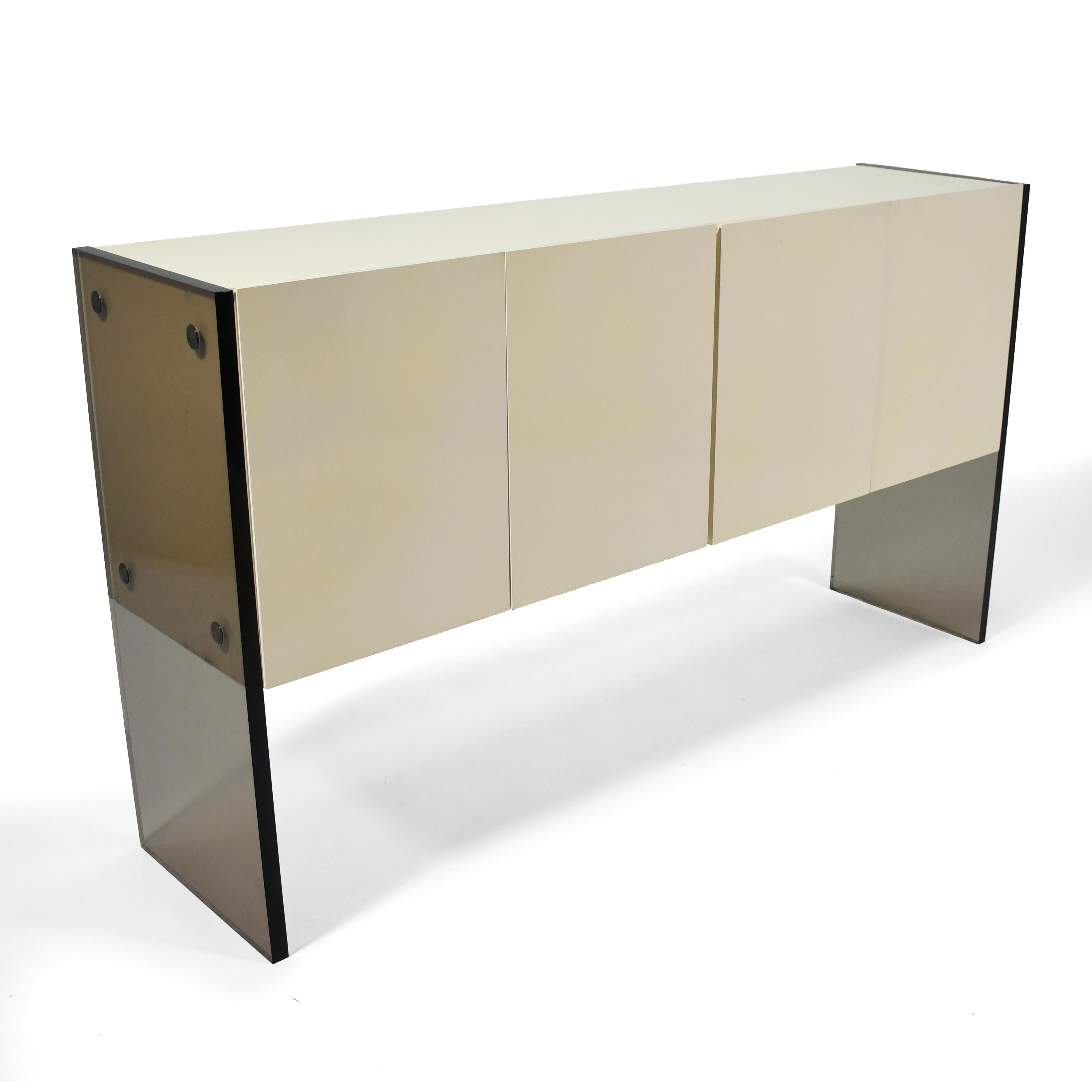 A strikingly beautiful minimalist design by Milo Baughman for Thayer Coggin, this credenza has a two-door cabinet in ivory lacquer suspended by legs of smoked lucite. Interior features an adjustable shelf, utensil drawers, and storage