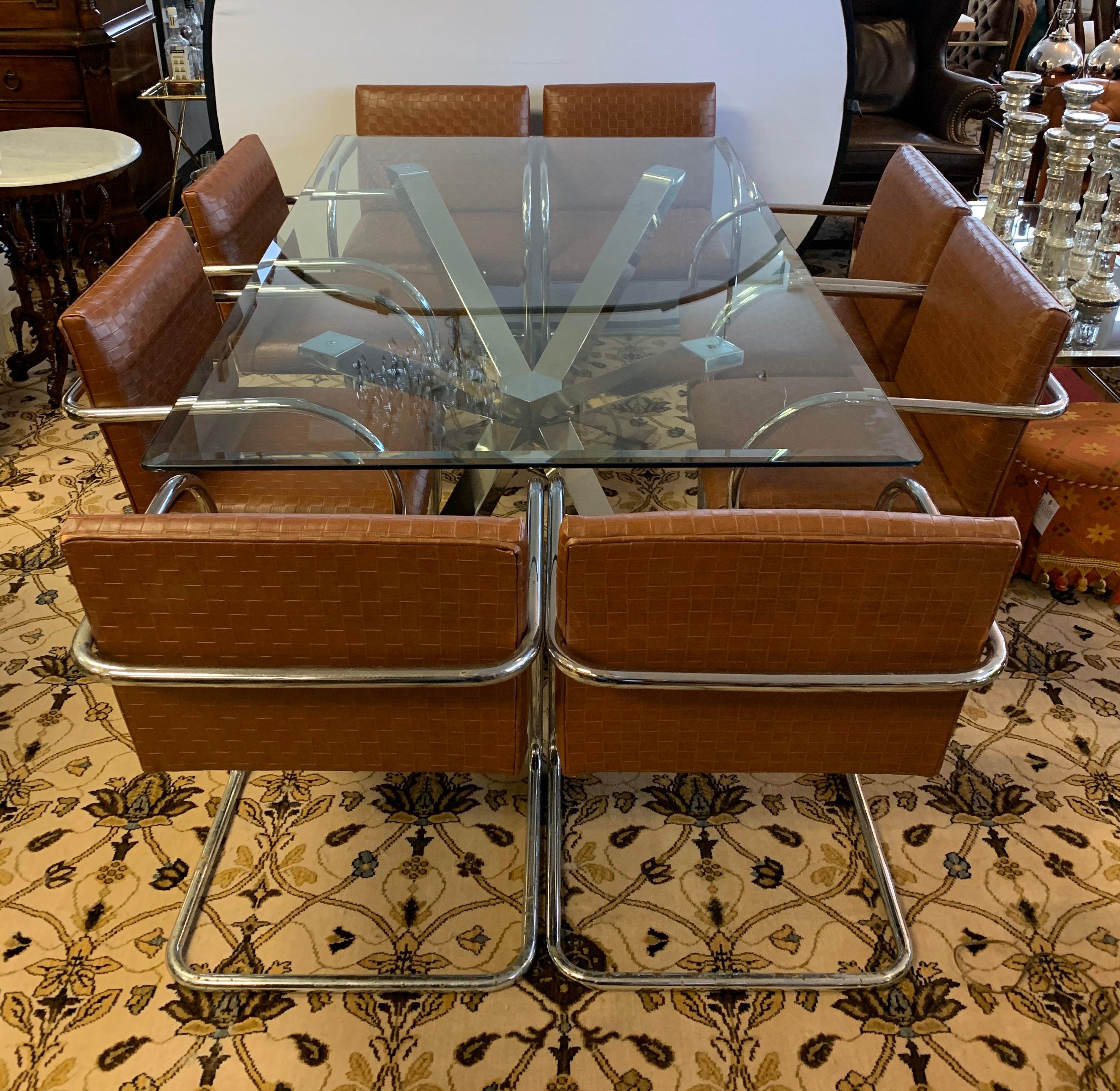 Milo Baughman style dining room set includes a set of eight leather and chrome cantilever chairs
that are from the 1970s and a more recent glass top dining table that sits atop a silver chrome X-base
base. The table is circa 21st century and is in