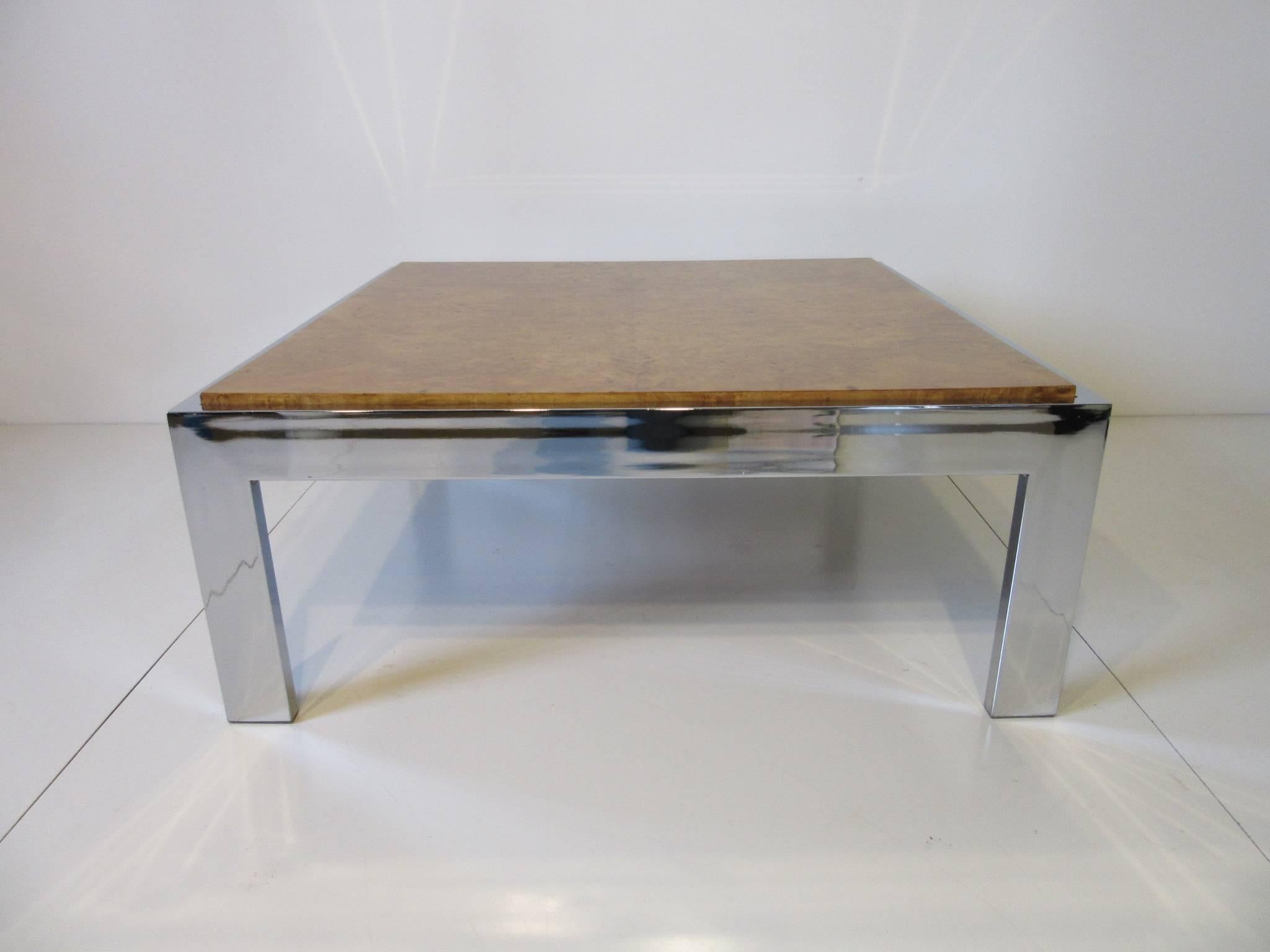 A elegant chrome framed coffee table with raised book matched olive wood burl inset table top, well made and having plastic foot caps to the legs bottoms to prevent hardwood floor scratches.