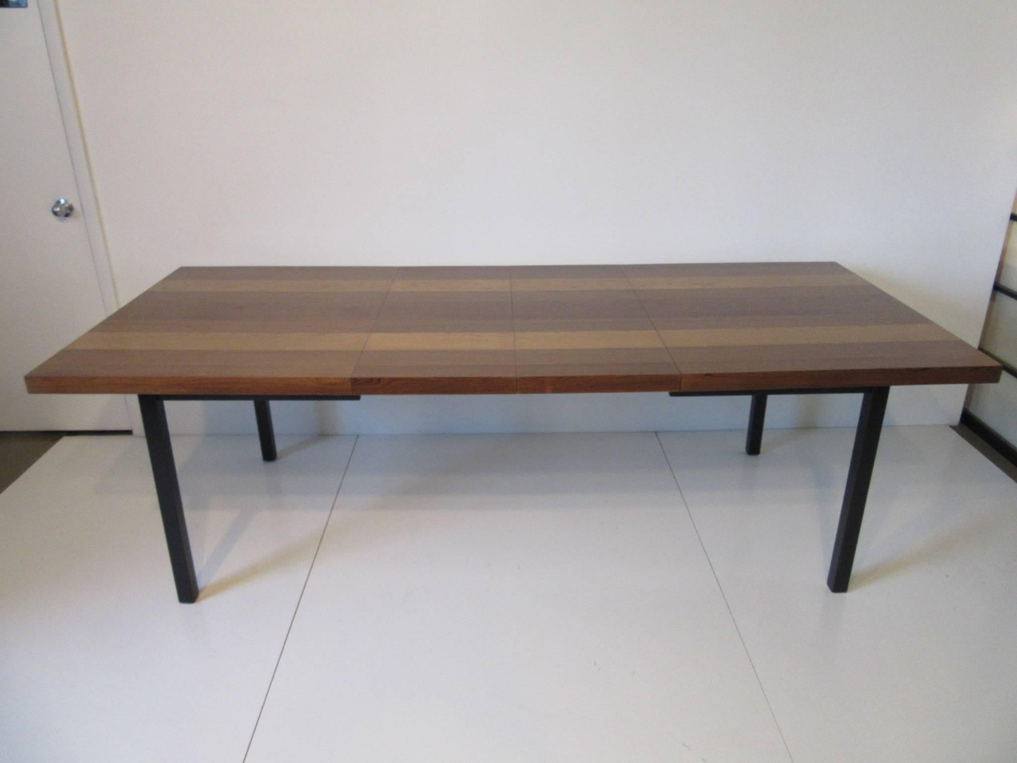A multi wood plank dining table using walnut , rosewood and ash to create a lux rich feel, satin black legs makes the table top seemly float . Includes two 15.50