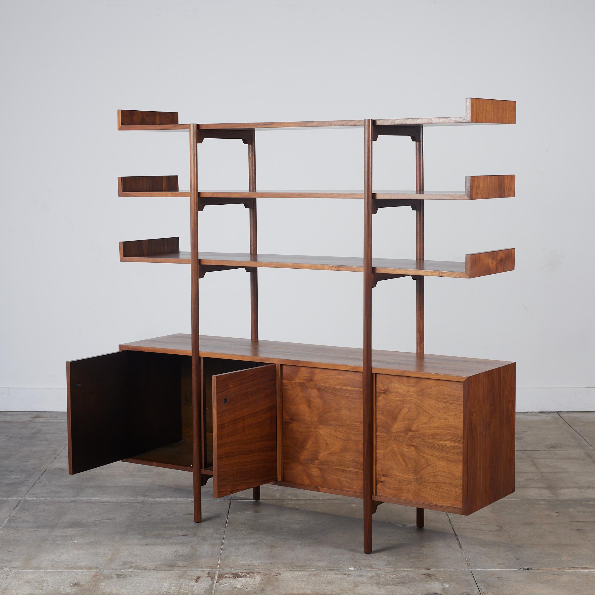 An architectural room divider by Milo Baughman for Glenn of California, c.1950s, USA. This stunning walnut storage unit features three floating shelves that can be used to showcases books and décor. The lower cabinet with adjustable shelving opens
