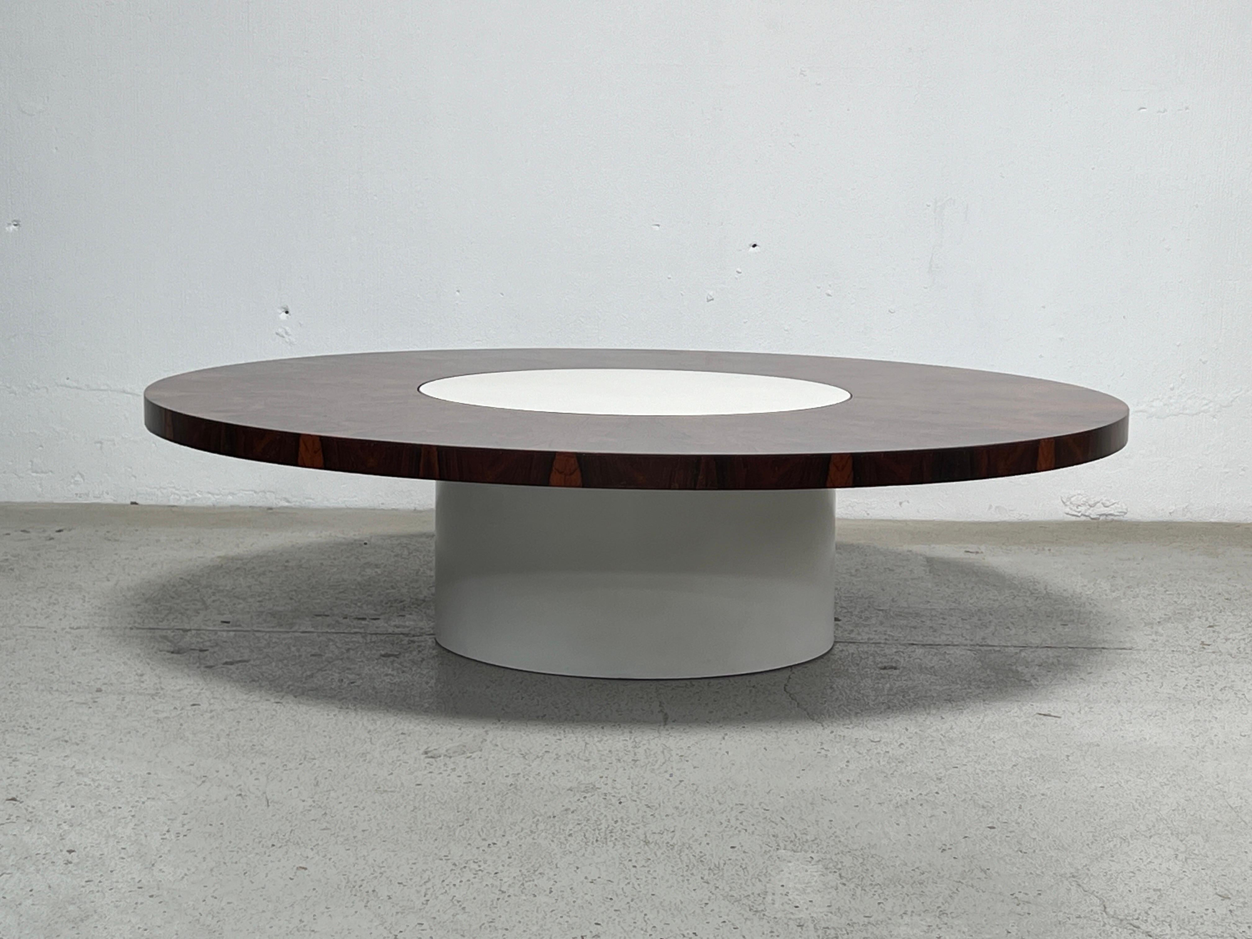 A large rosewood Milo Baughman coffee table with white lacquered base. The rosewood section spins around the white center section. 