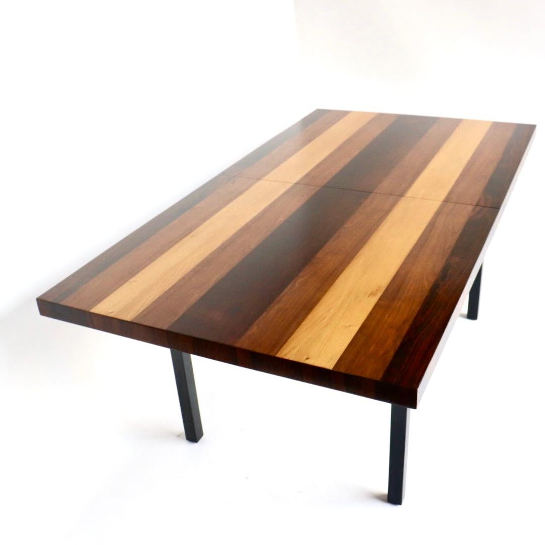 Milo Baughman designed this  mixed wood dining table for Directional circa 1960s. Baughman chose the three types of wood for their contrasting nature to each other. The 3 types of wood: rosewood, walnut, and oak This table expands dramatically and
