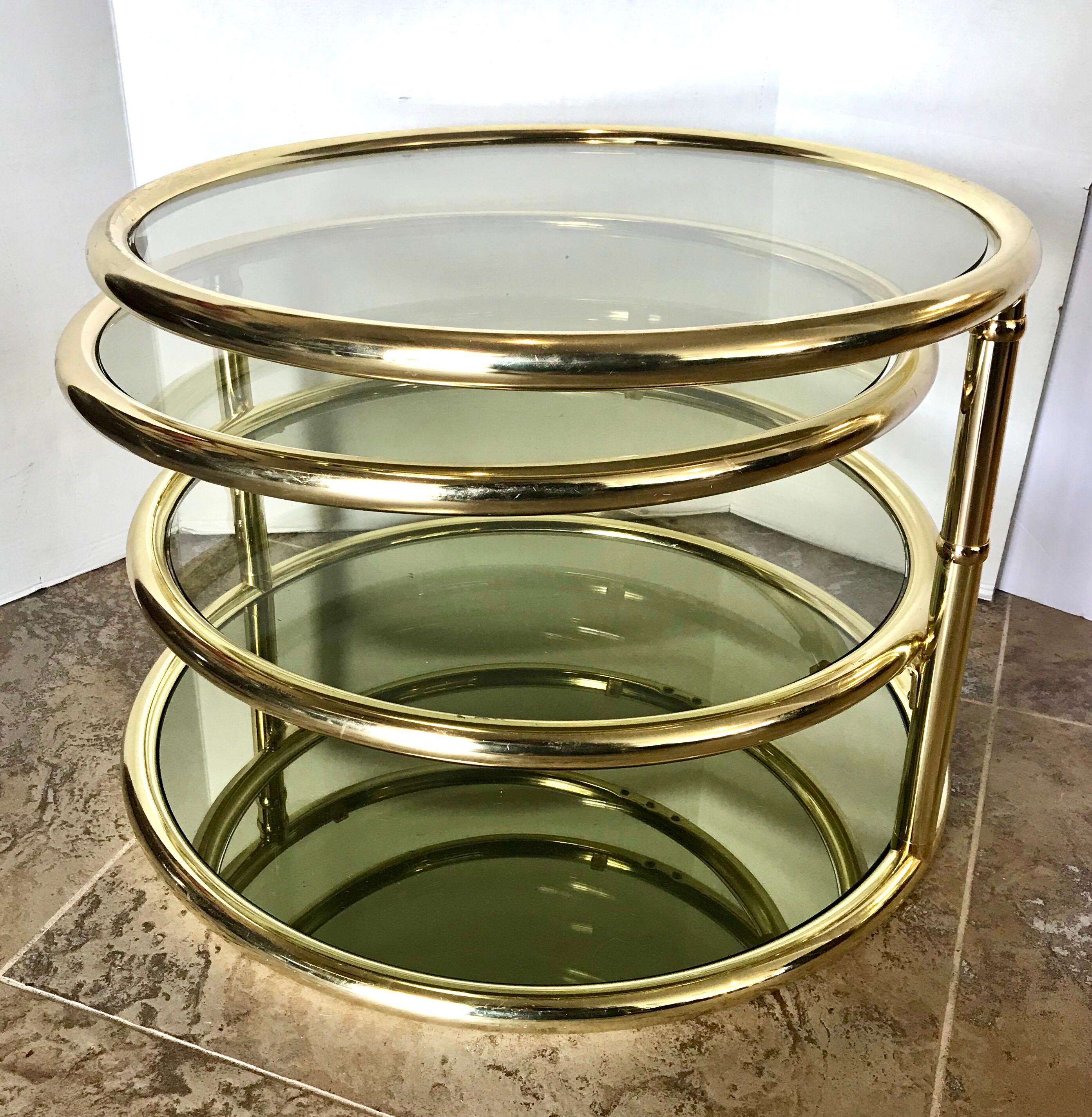 Mid century modern Milo Baughman four tiered brass and glass cocktail or end table. The top two tiers swivel out to expand the table. There are four levels altogether with diameters of 28