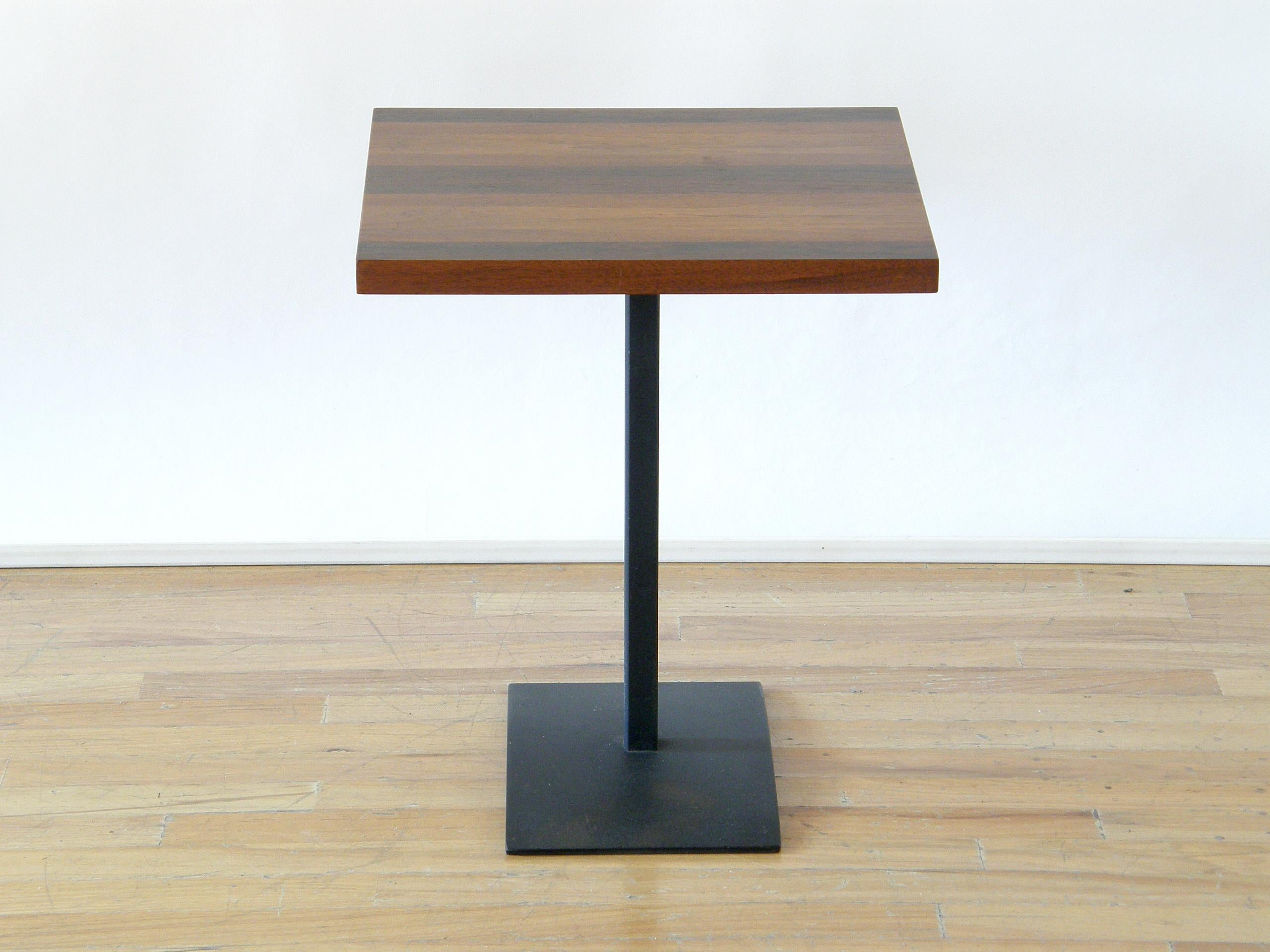 This petite side table or drink stand was designed by Milo Baughman for Directional. The steel base has a matte black finish, and the foot plate has an elegant subtle arch. The top has a striped veneer pattern using different woods that creates a