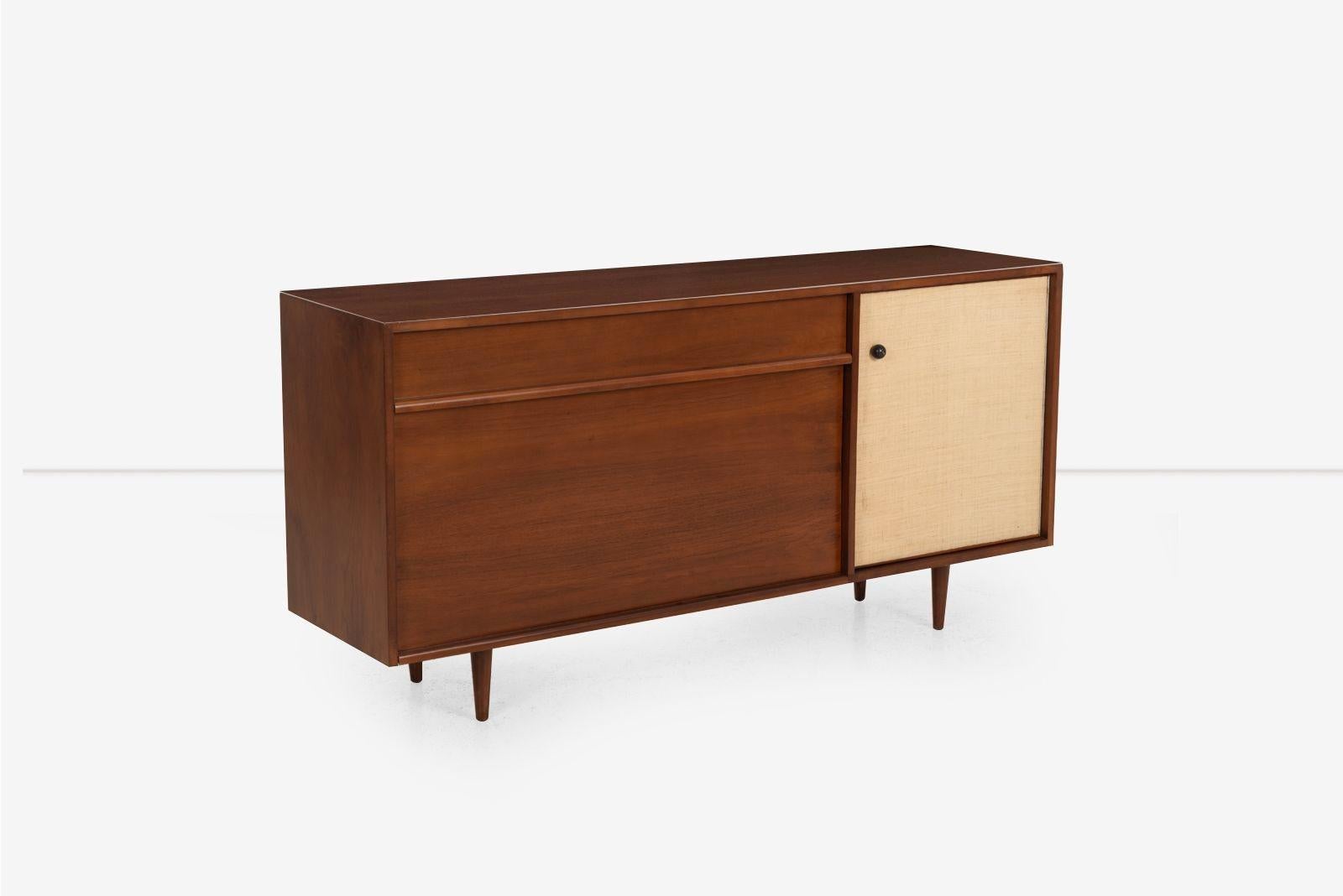 Milo Baughman Sideboard for Glenn of California, 1955 Model 1632
Restored walnut sideboard featuring a long drawer beneath a tambour-style garage door that opens and hides for maximum clearance. The grasscloth-covered door reveals an interior cubby