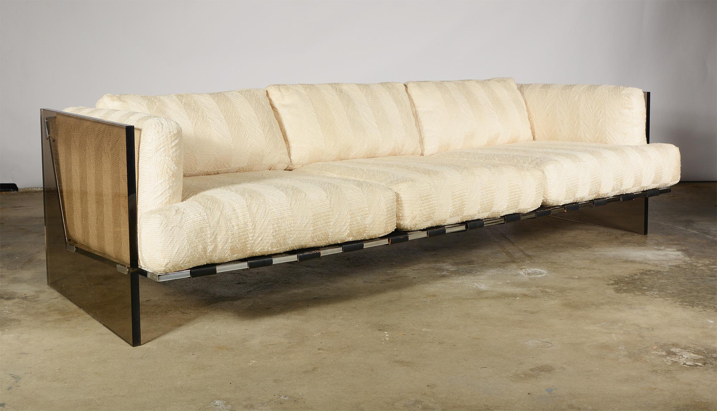 Three-seat sofa with slab smoked bronze acrylic sides by Milo Baughman. This chair has a chrome frame with wide black leather straps to support the cushions. The acrylic shows light wear. One side has a couple of scratches, a deep scratch on the